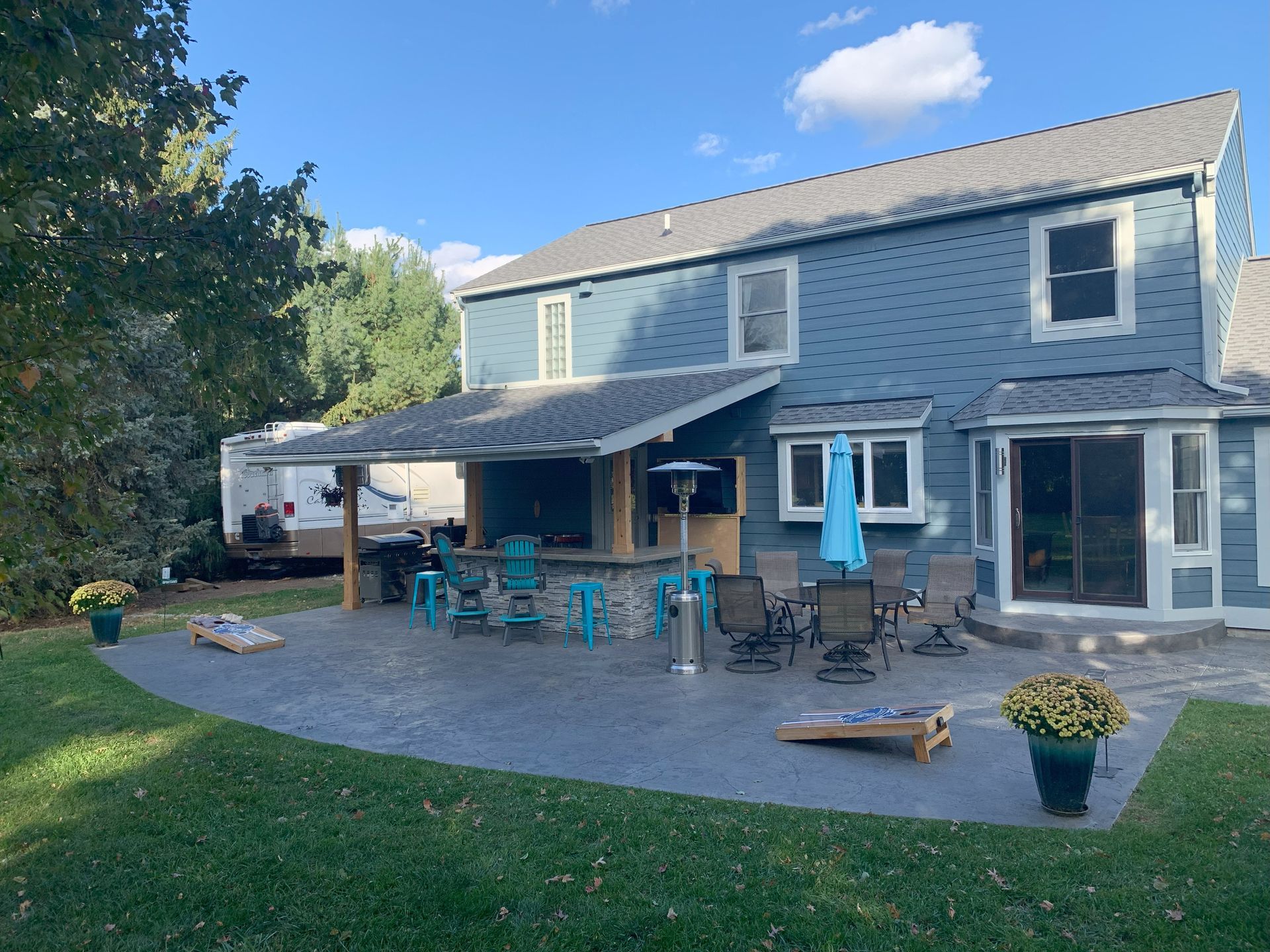Backyard patio with outdoor dining set, lounge chairs, and a two-story house in daylight