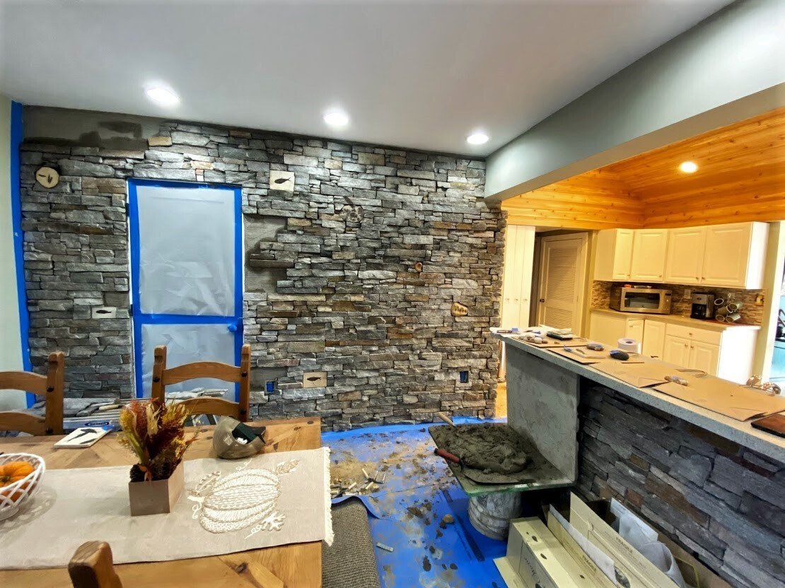 Stone-walled kitchen and dining area with blue floor covering and wood-paneled pass-through counter
