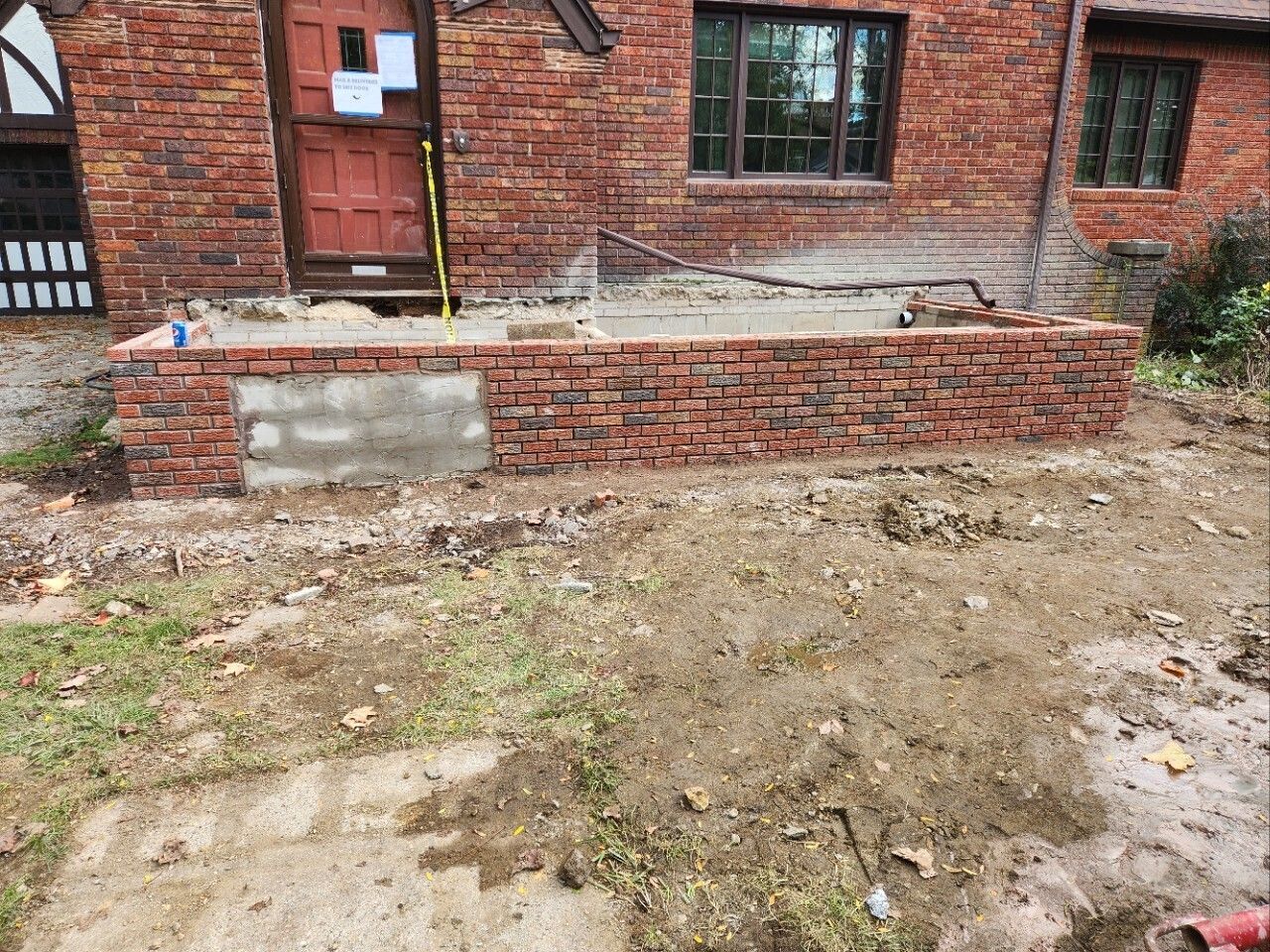 Brick building with a low brick planter and muddy dirt courtyard in front