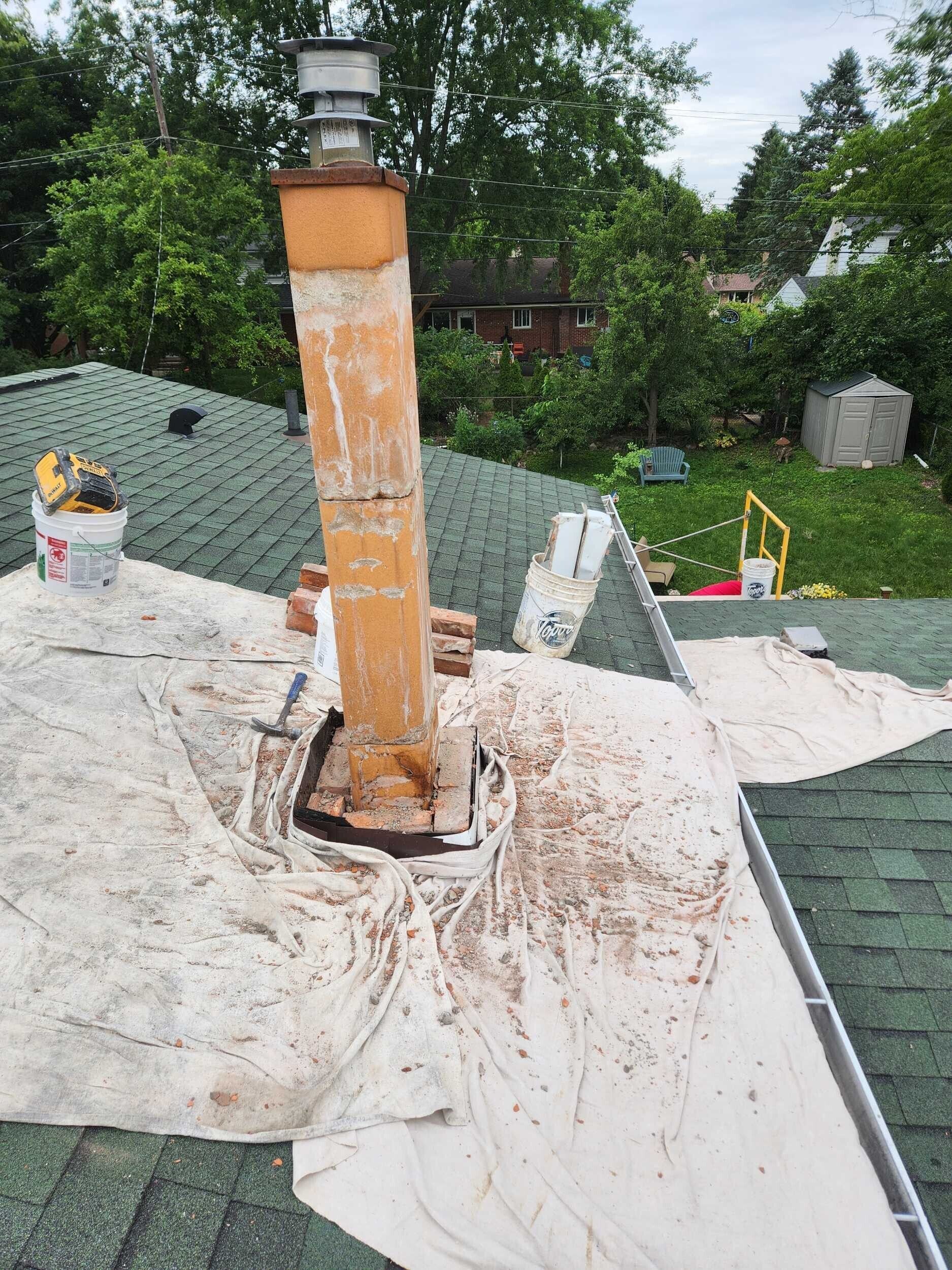 Damaged rooftop chimney pipe with rusted base amid white roofing material and nearby trees
