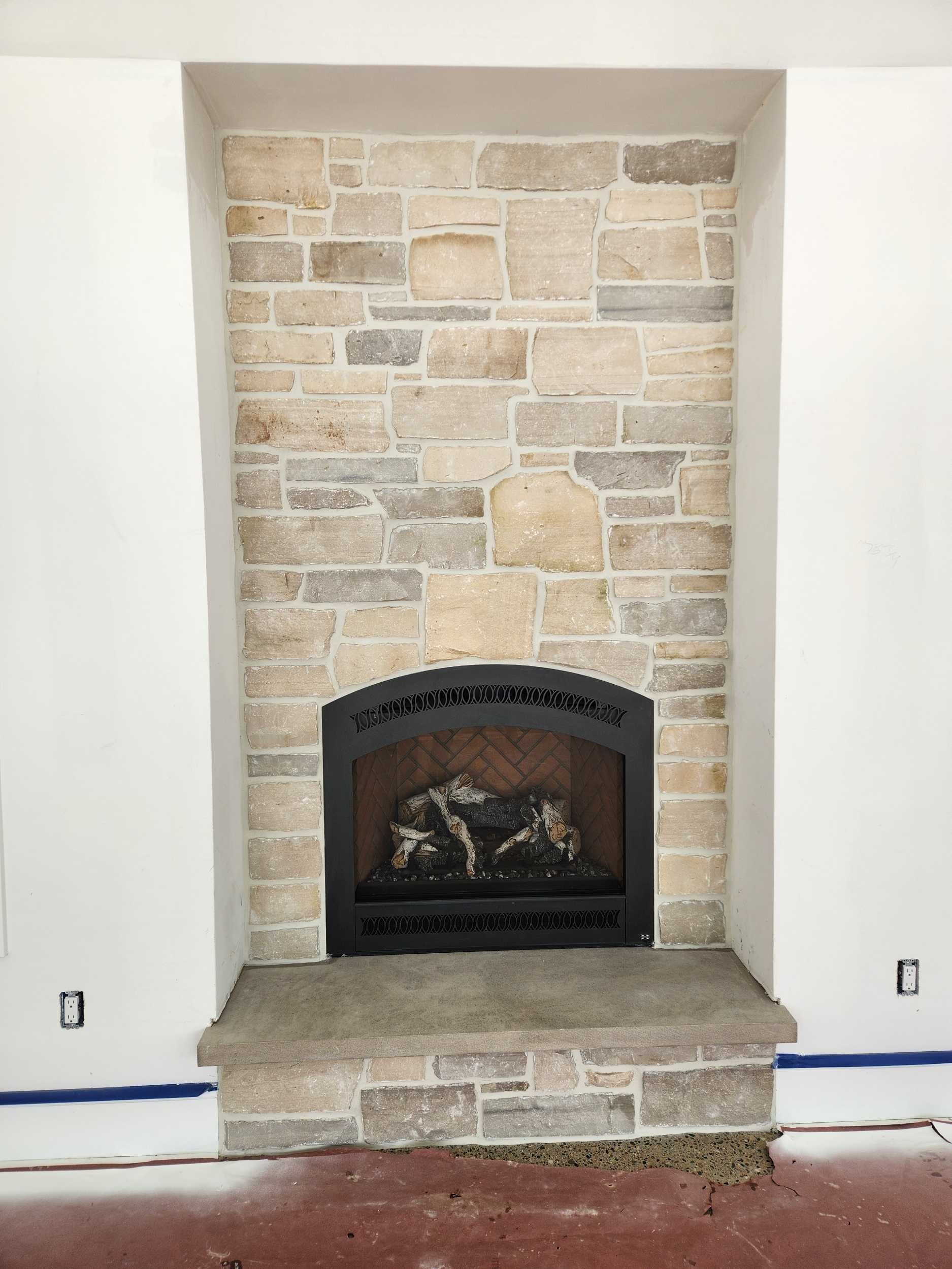 Stone fireplace with beige stacked-stone surround and black firebox in a recessed wall.