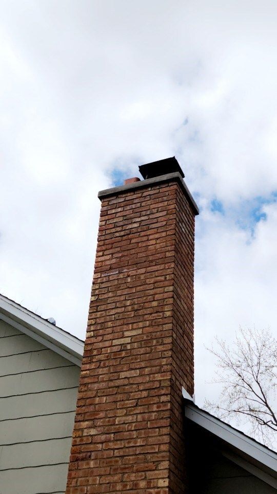 Brick chimney on a house roof against a cloudy sky