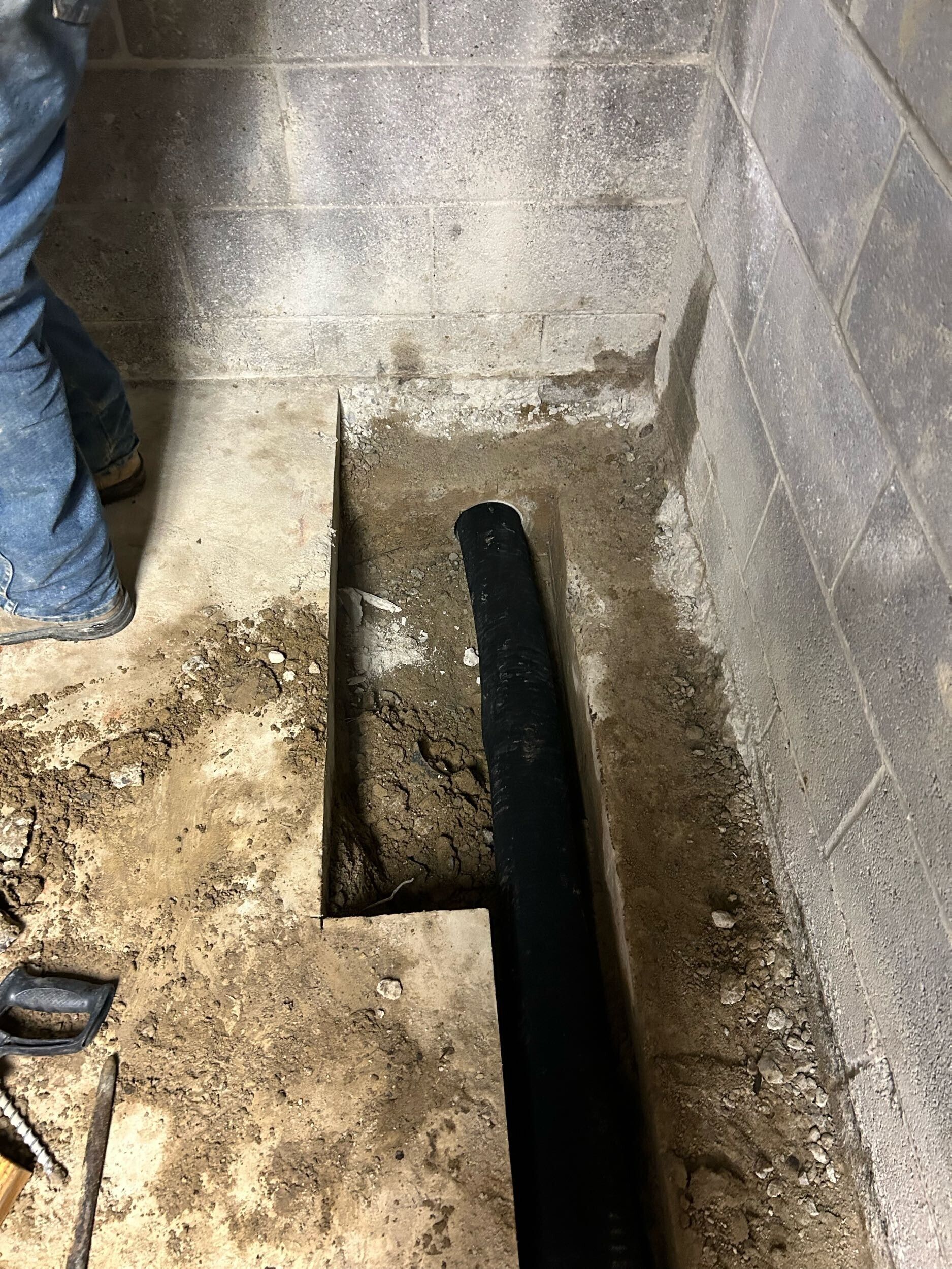 Concrete utility trench with a narrow channel and a person’s leg at the left edge