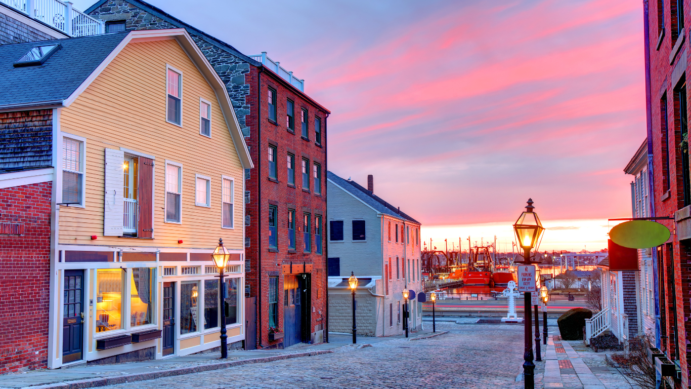 A row of buildings on a cobblestone street with a sunset in the background.