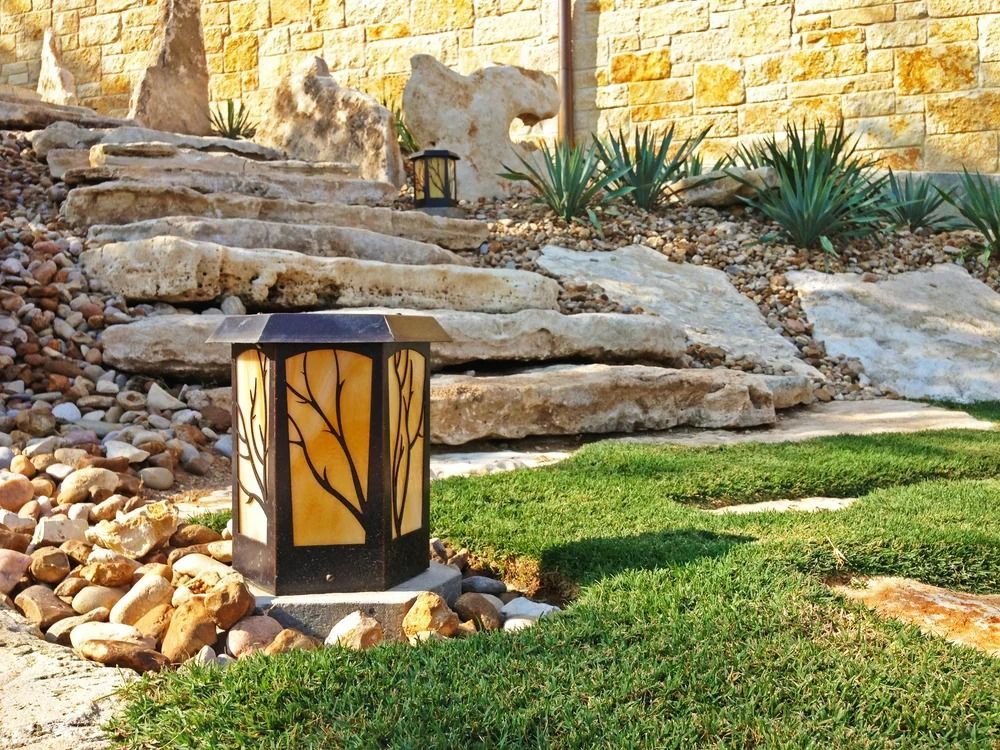Stone steps with a decorative lamp in a landscaped yard.