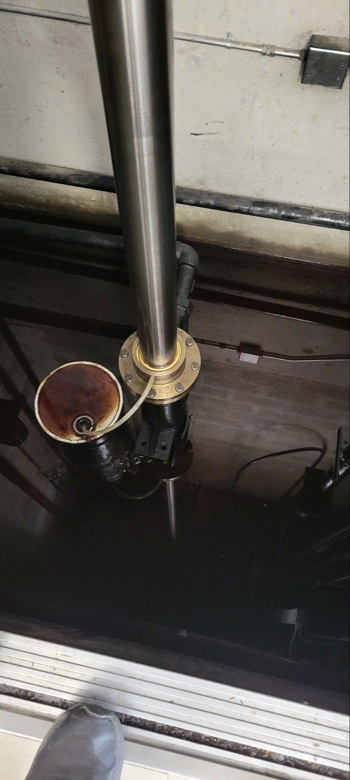 Metal pipes and a copper bowl mounted on a dark industrial ceiling, with wiring visible below.