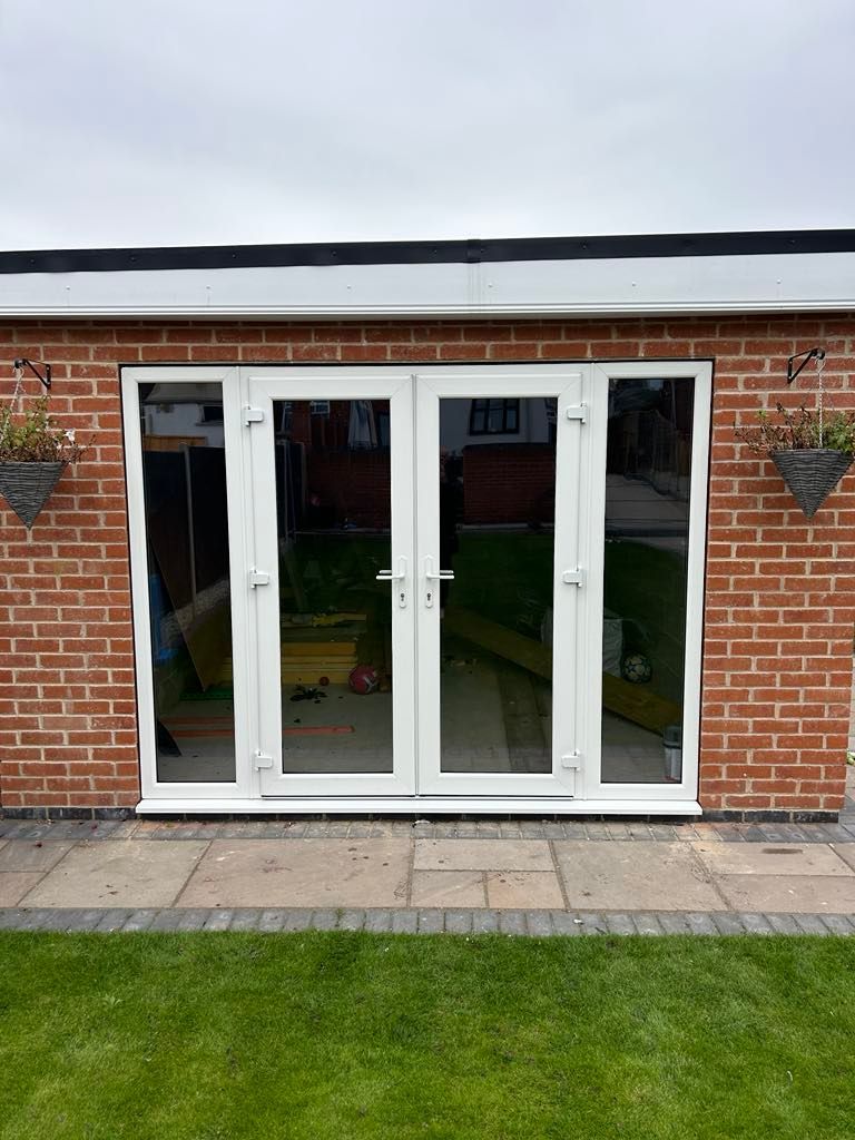 A patio with a table and chairs in front of a house with french doors