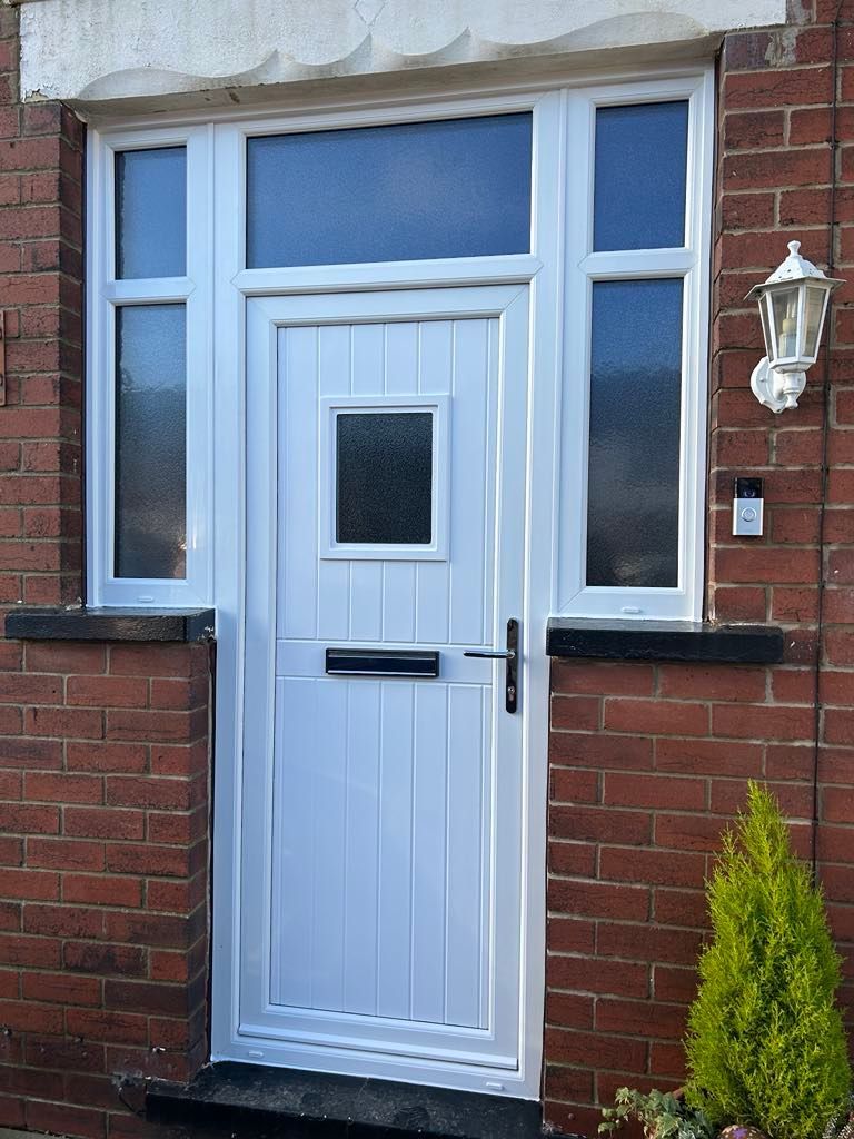 A white door is sitting on a brick wall next to a lamp.