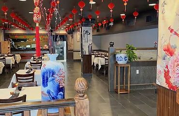 Restaurant interior with red lanterns, tables, and a blue decorative lion statue near the entrance