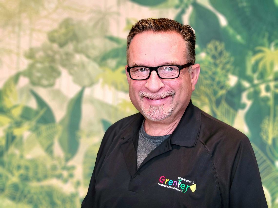 A man wearing glasses and a black shirt is smiling for the camera.