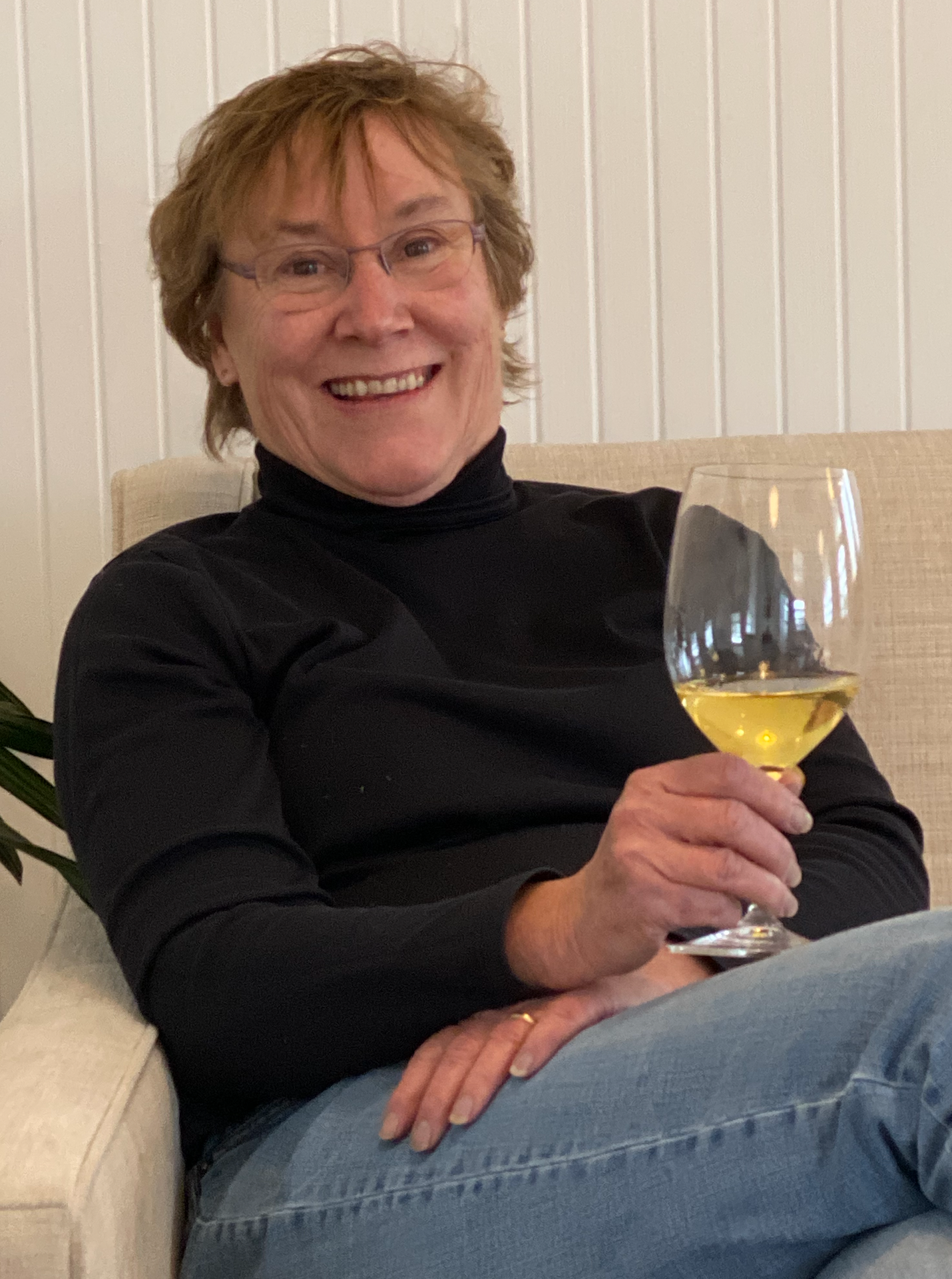Kathy Shiels, CEO and founder smiling with a glass of Chardonnay