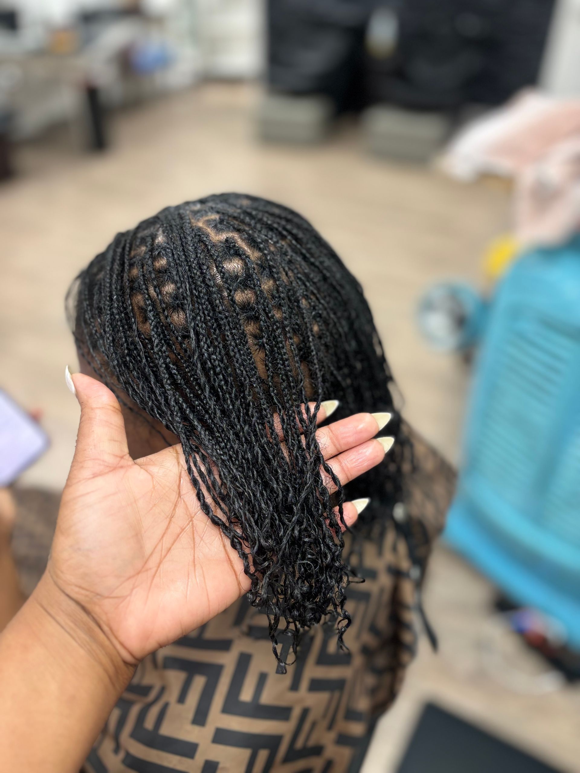 A woman with braids in a ponytail is sitting in a chair. A woman with braids in a ponytail is sitting in a chair.