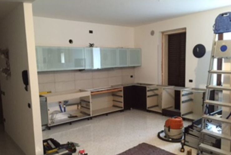 Lastre di vetro verticali di diverse altezze sono disposte in fila sotto un soffitto di lamiera ondulata.