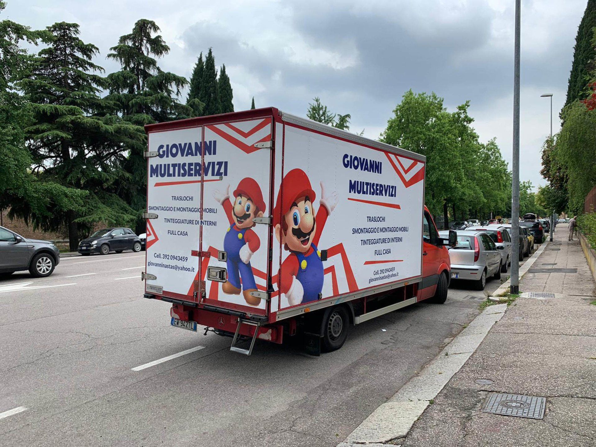 In un'officina, due operai sollevano un grande pannello rettangolare di vetro riflettente.
