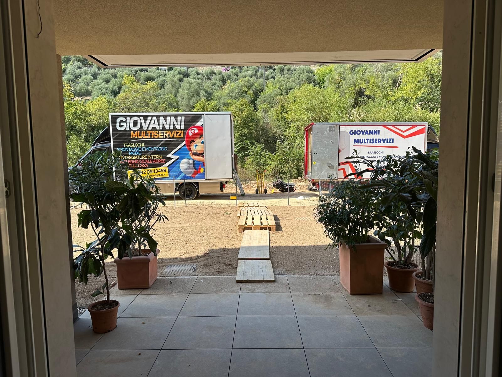 In un'officina, due operai sollevano un grande pannello rettangolare di vetro riflettente.
