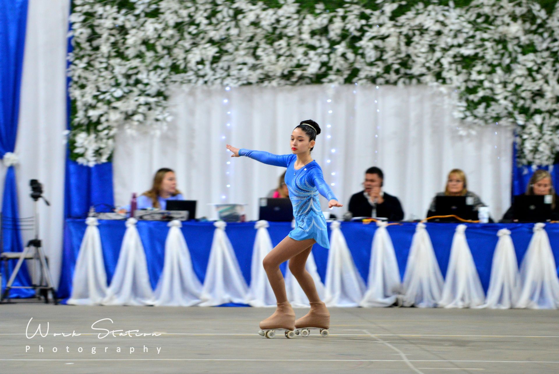 Una patinadora con un vestido azul realiza su actuación en una pista de patinaje 