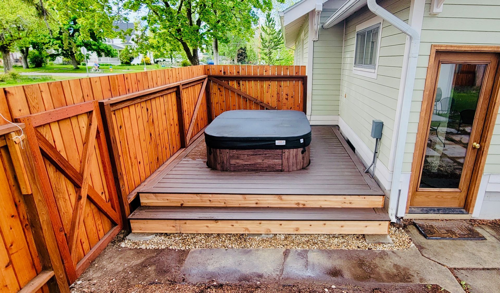 A hot tub is sitting on a wooden deck in front of a house.