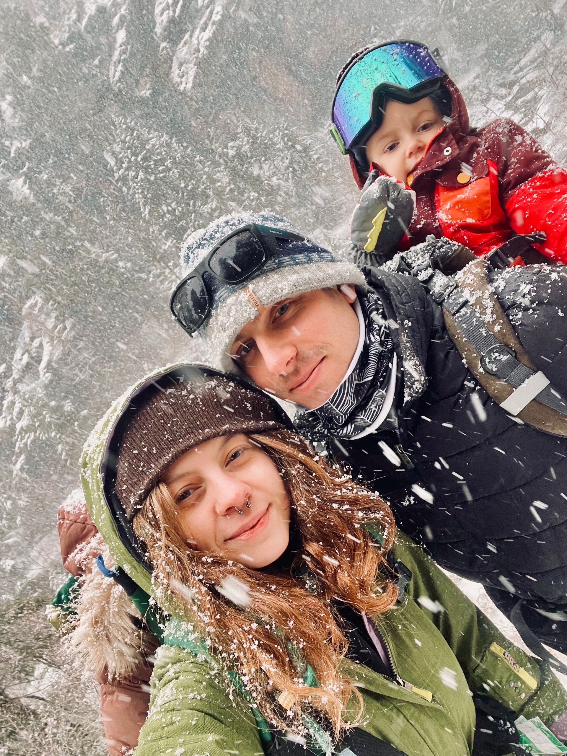 A man , woman and child are posing for a picture in the snow.