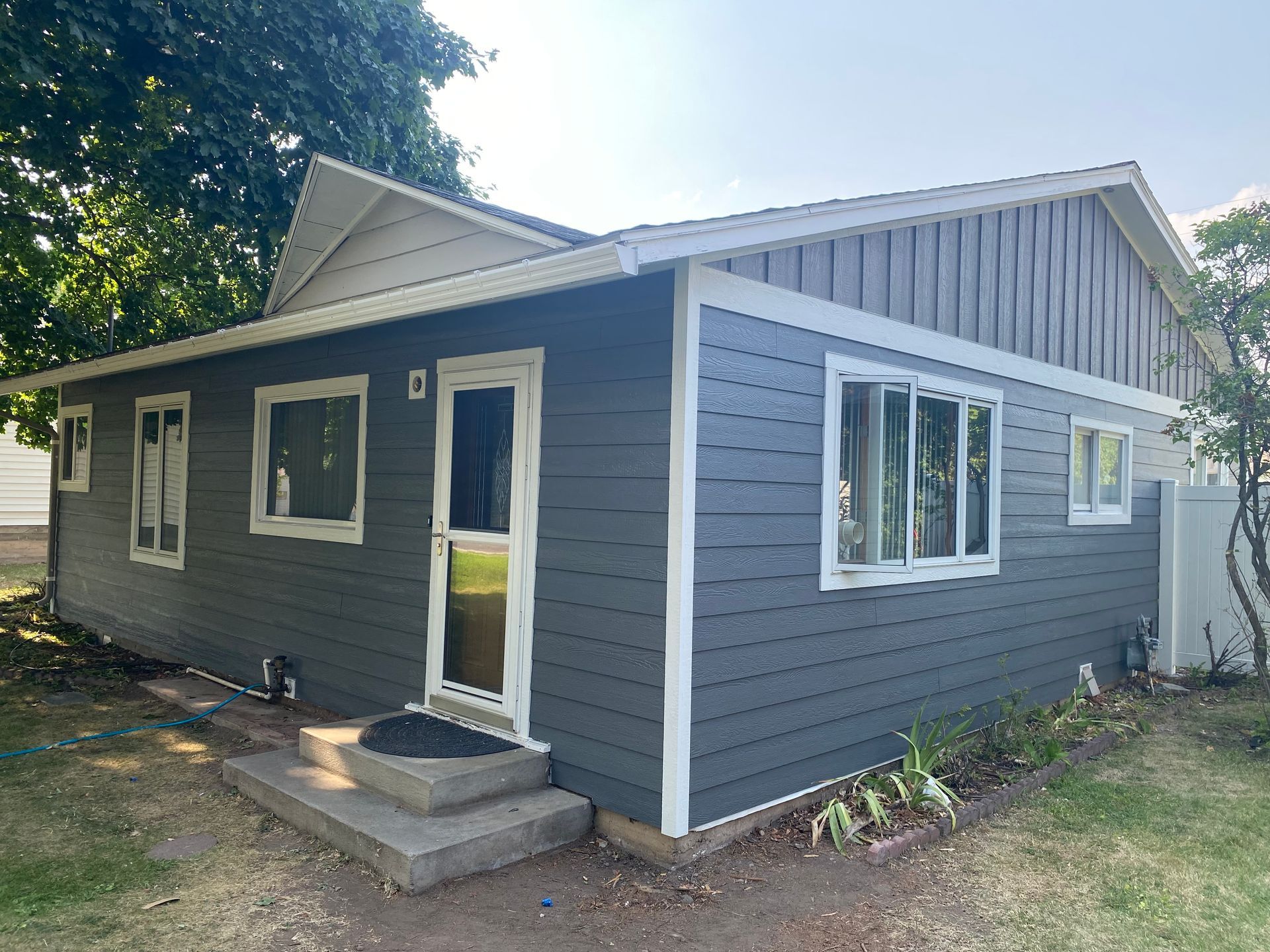 A small house with a gray siding and white trim.
