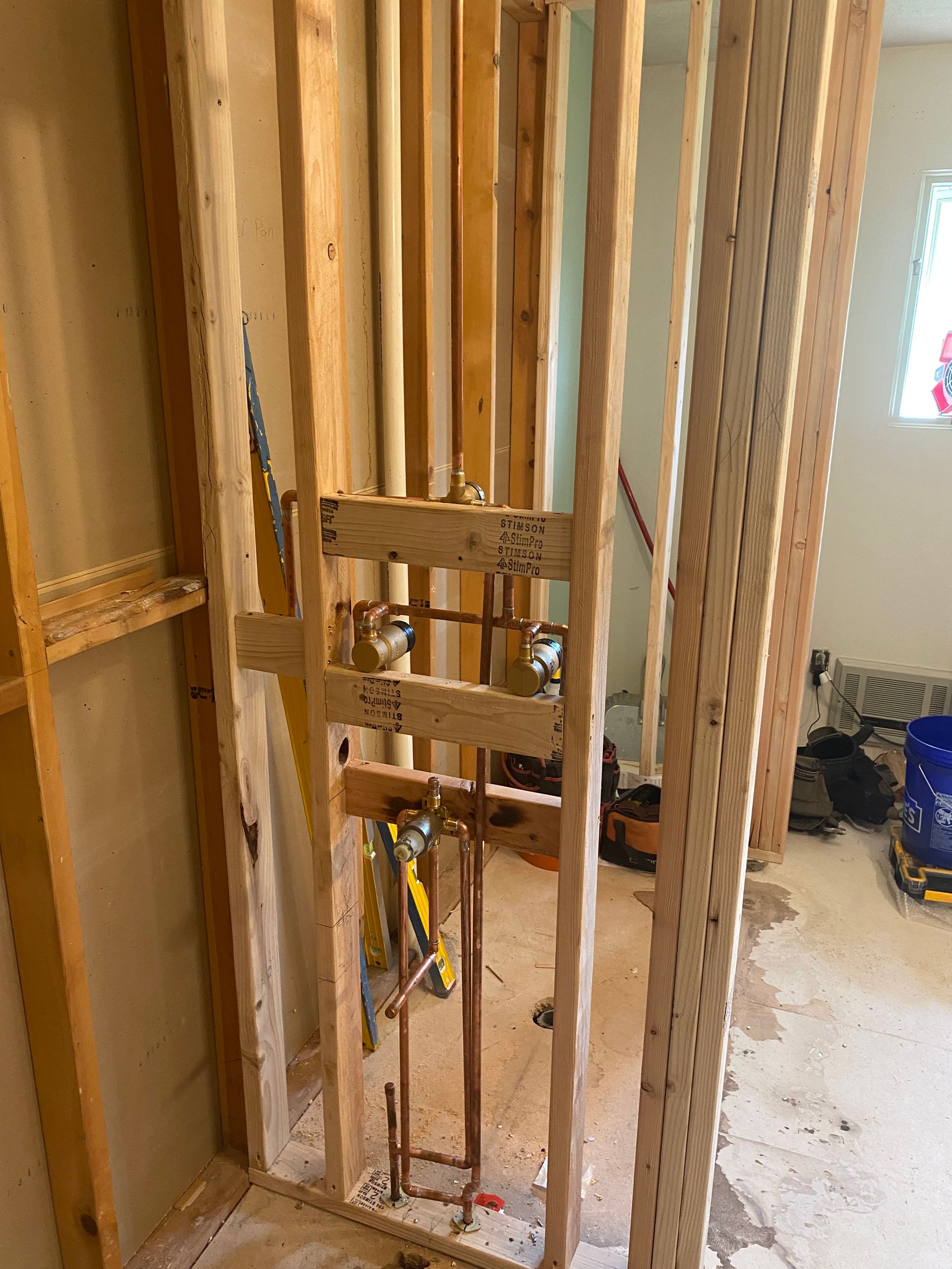 A bathroom under construction with a wooden frame and pipes.
