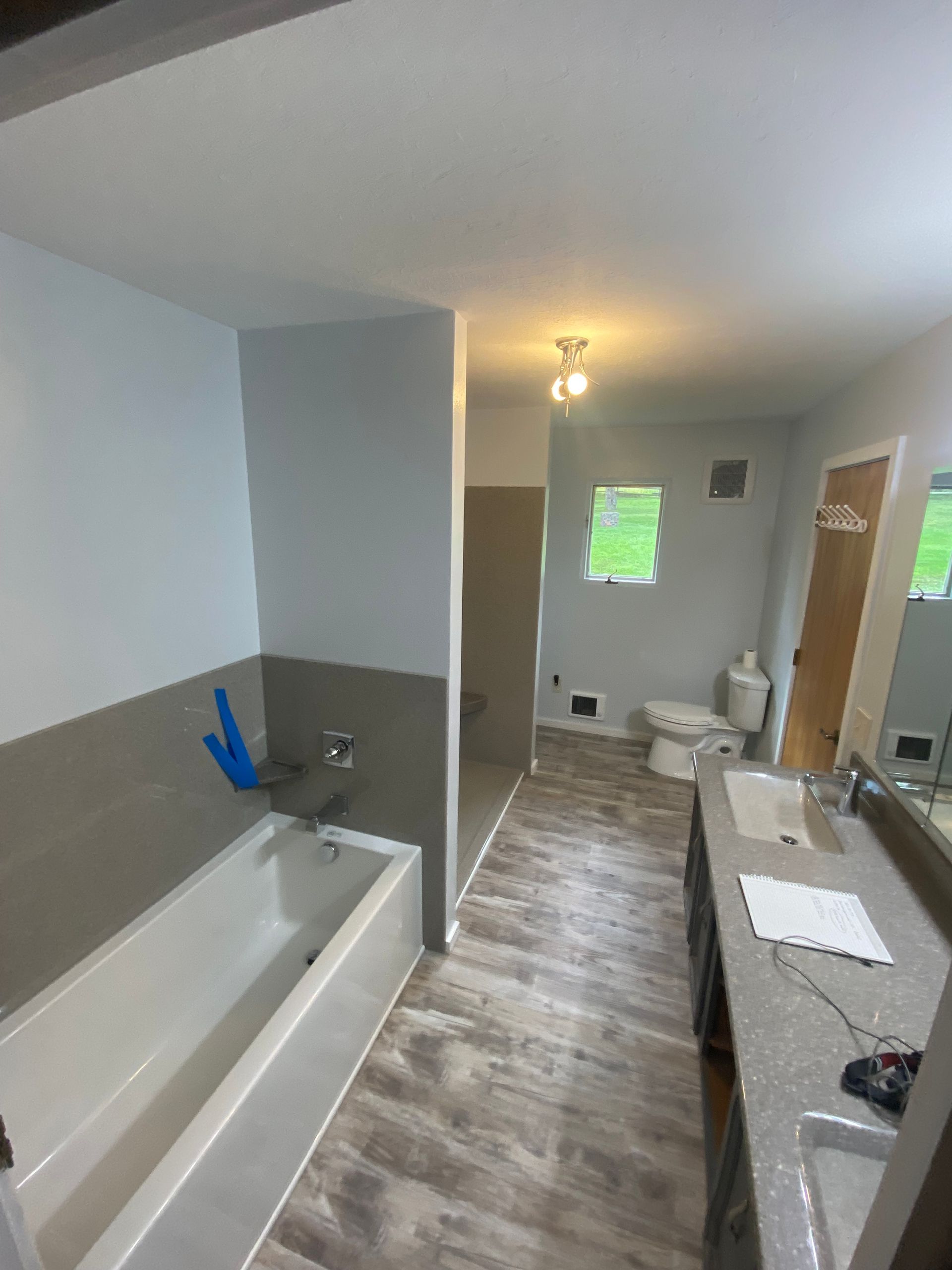 A bathroom with a tub , sink , toilet and mirror.