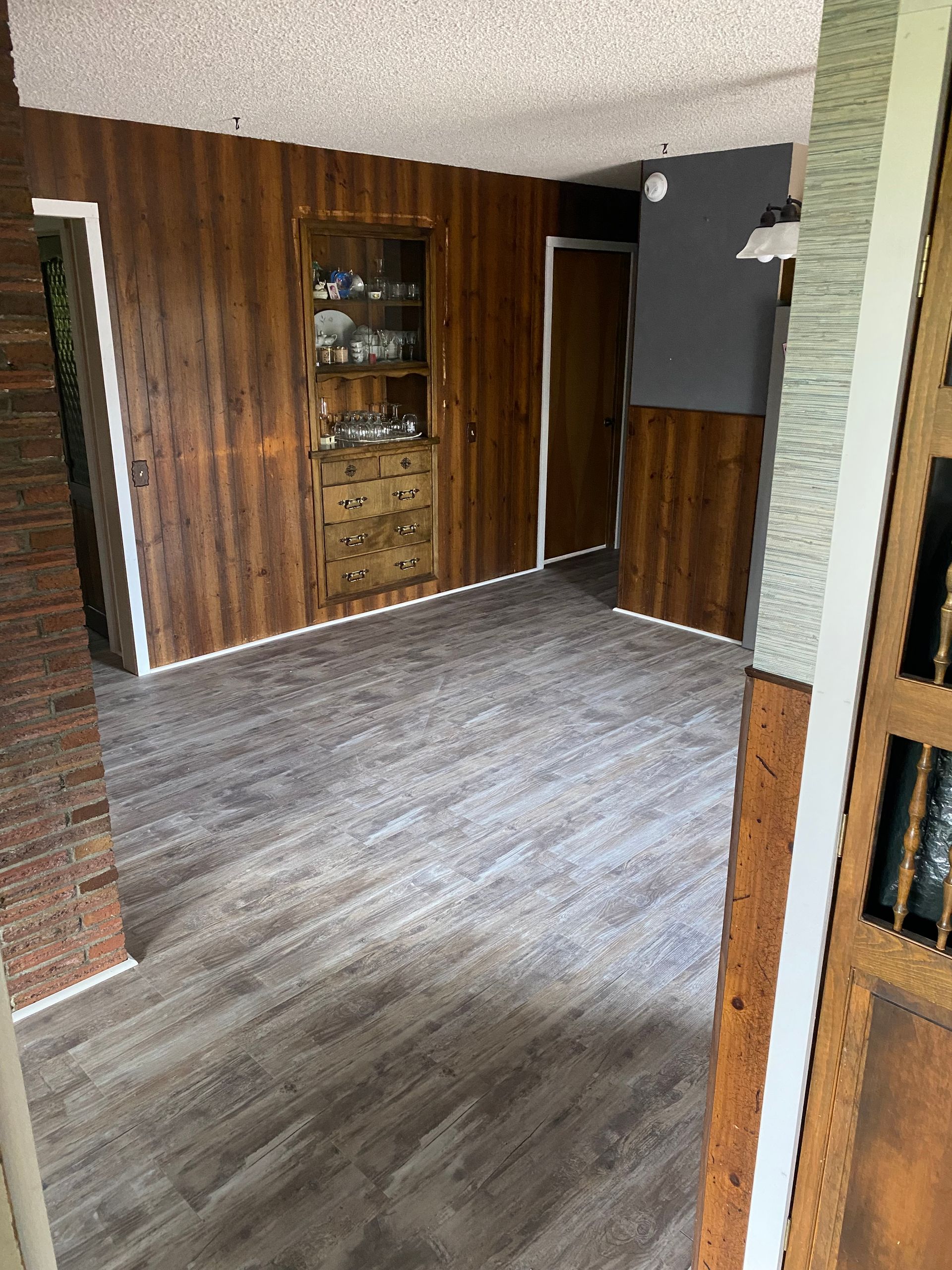 A room with hardwood floors and wood paneling on the walls.