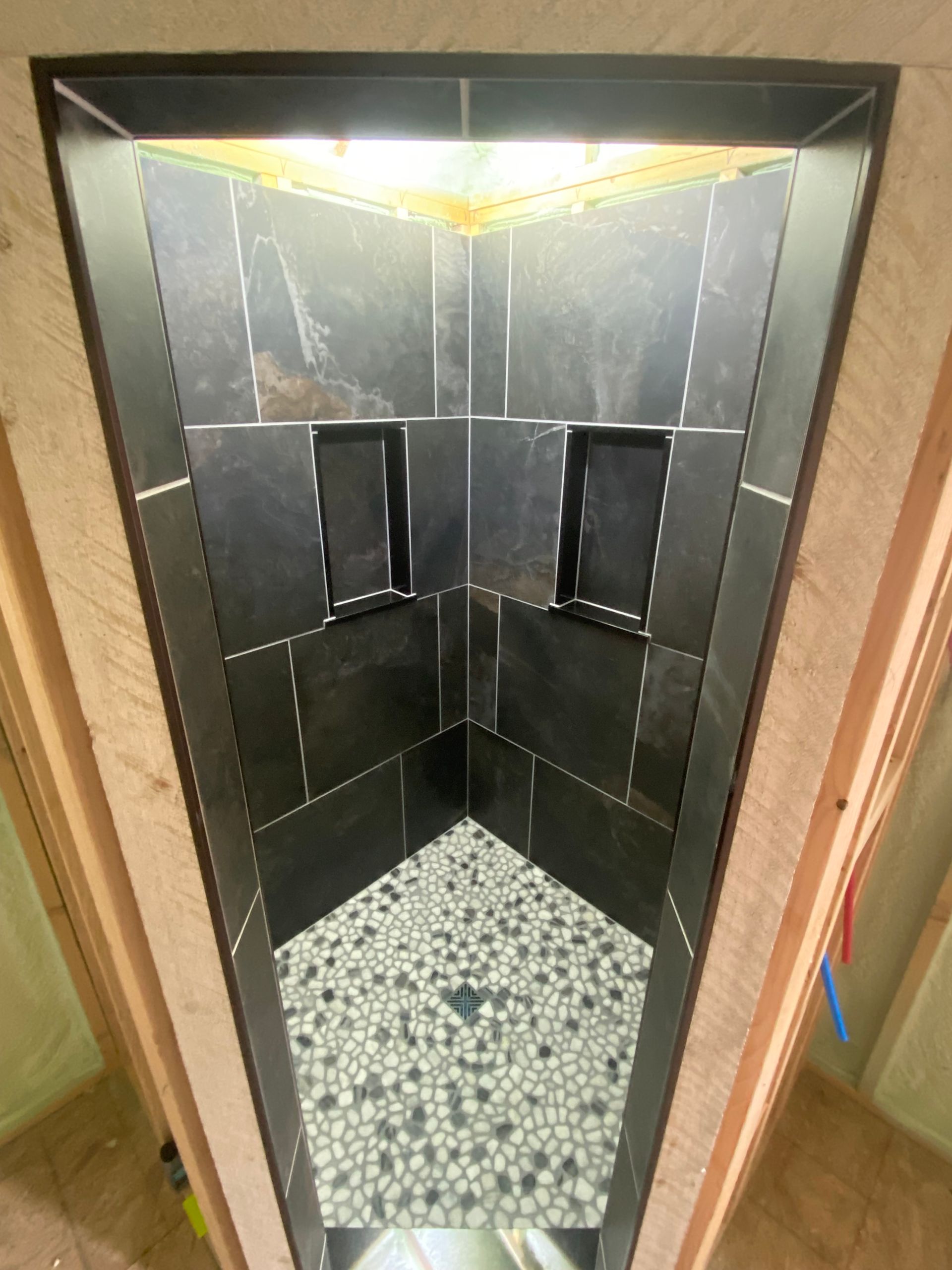 A bathroom with black tiles and a mosaic floor.