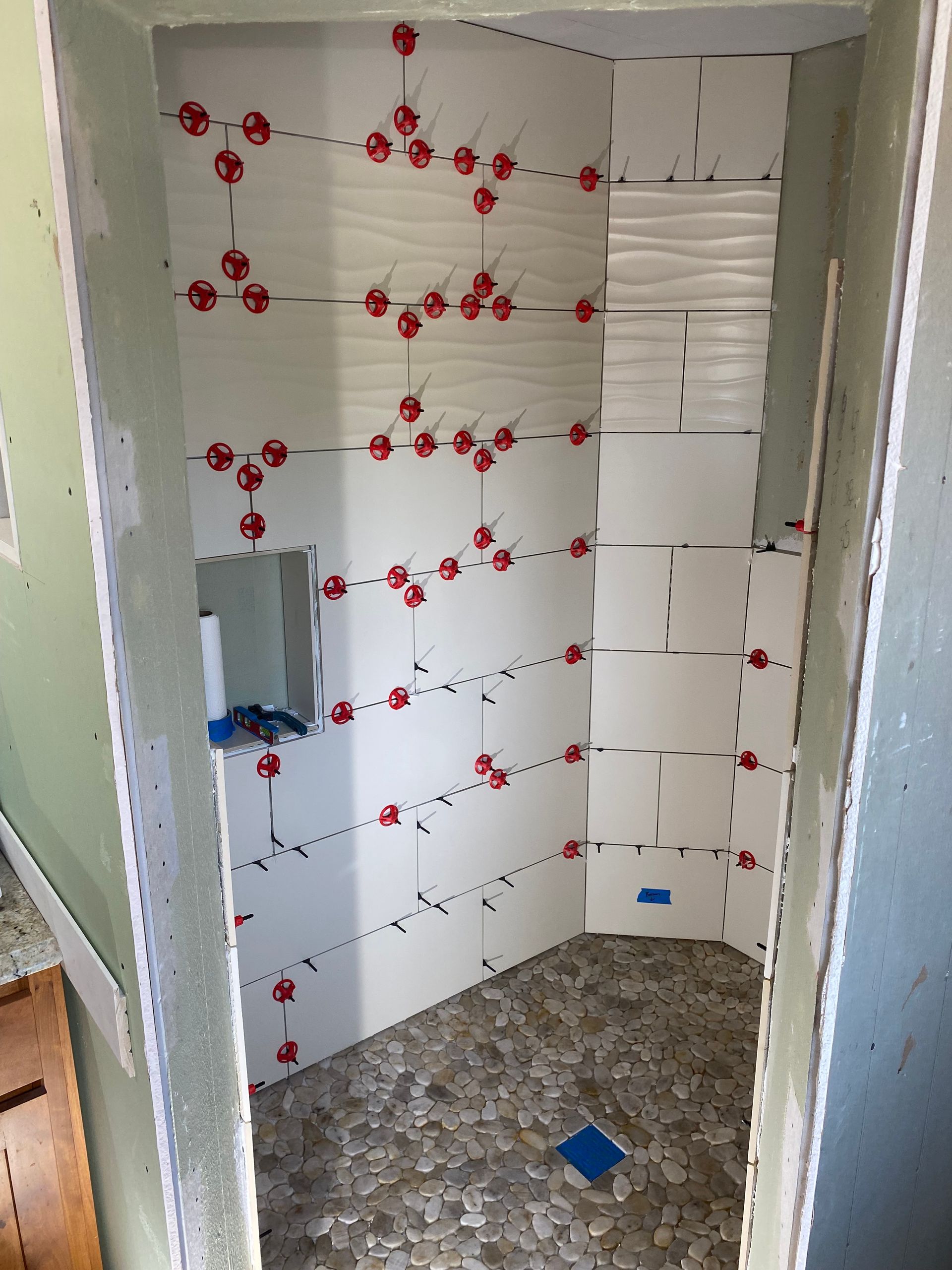 A bathroom being remodeled with white tiles and red spacers