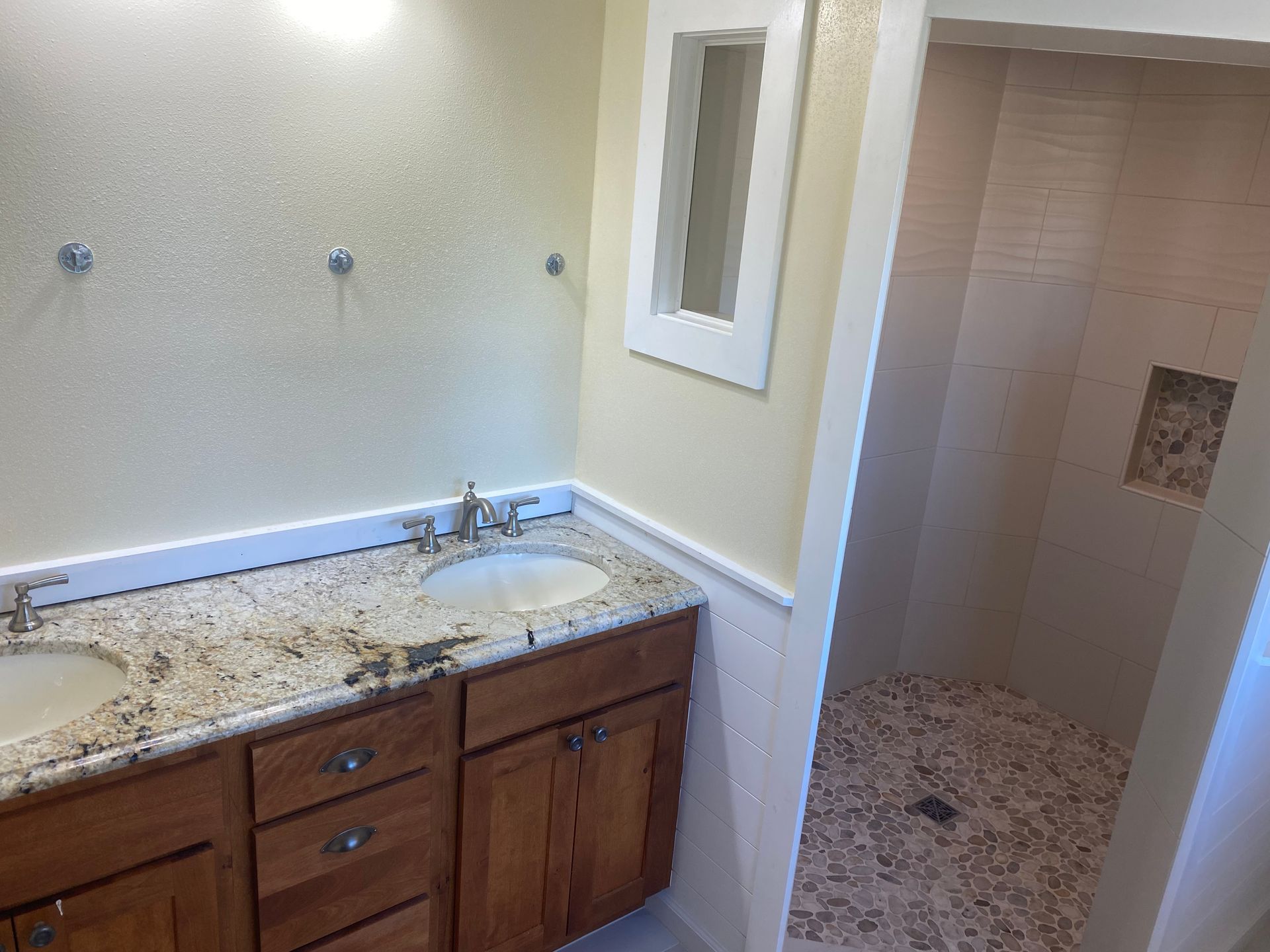 A bathroom with two sinks and a walk in shower.