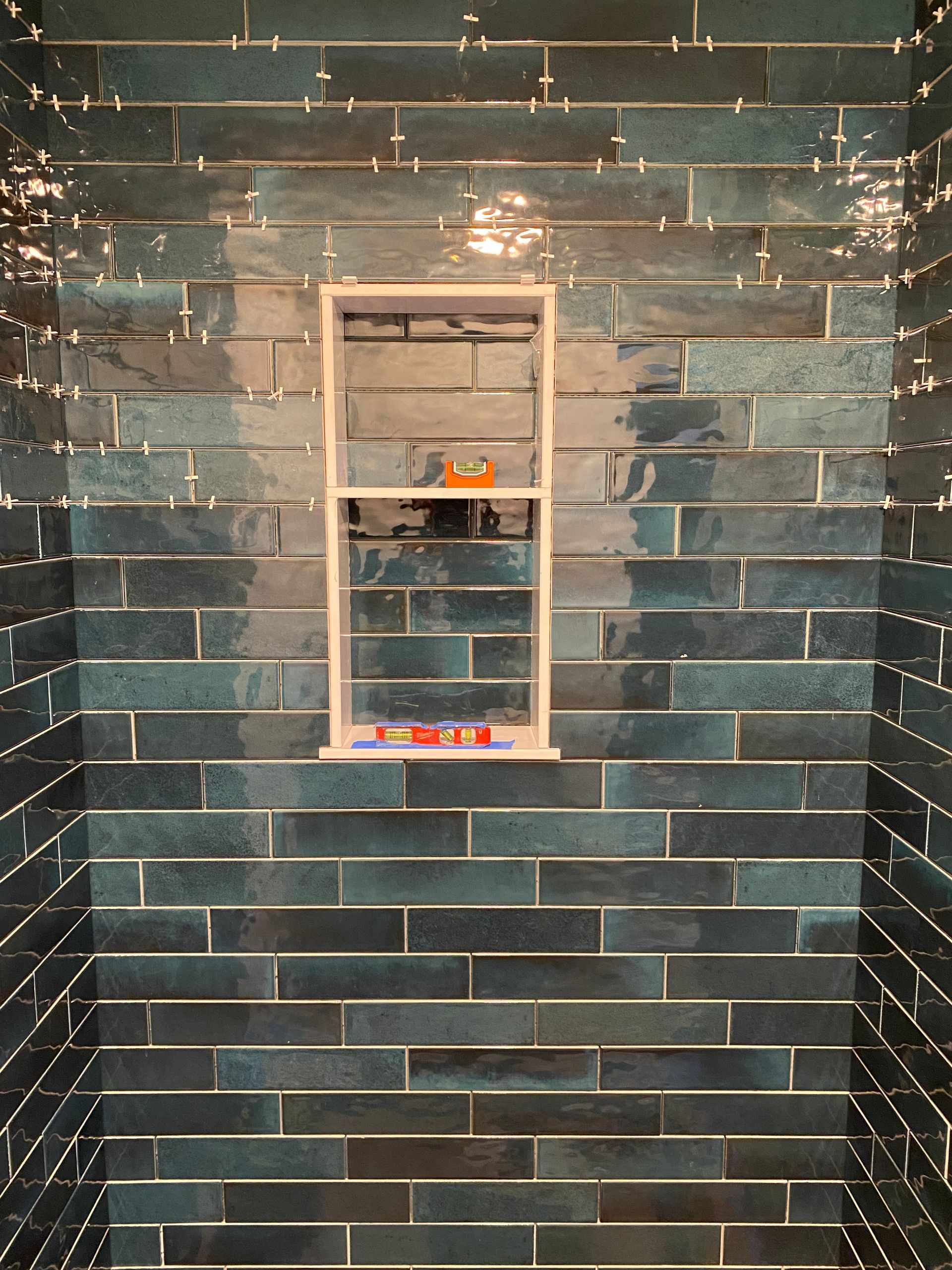 A bathroom with blue tiles and a window in the wall