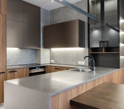 Modern kitchen with wood cabinets, gray island countertop, and stainless steel sink under soft lighting