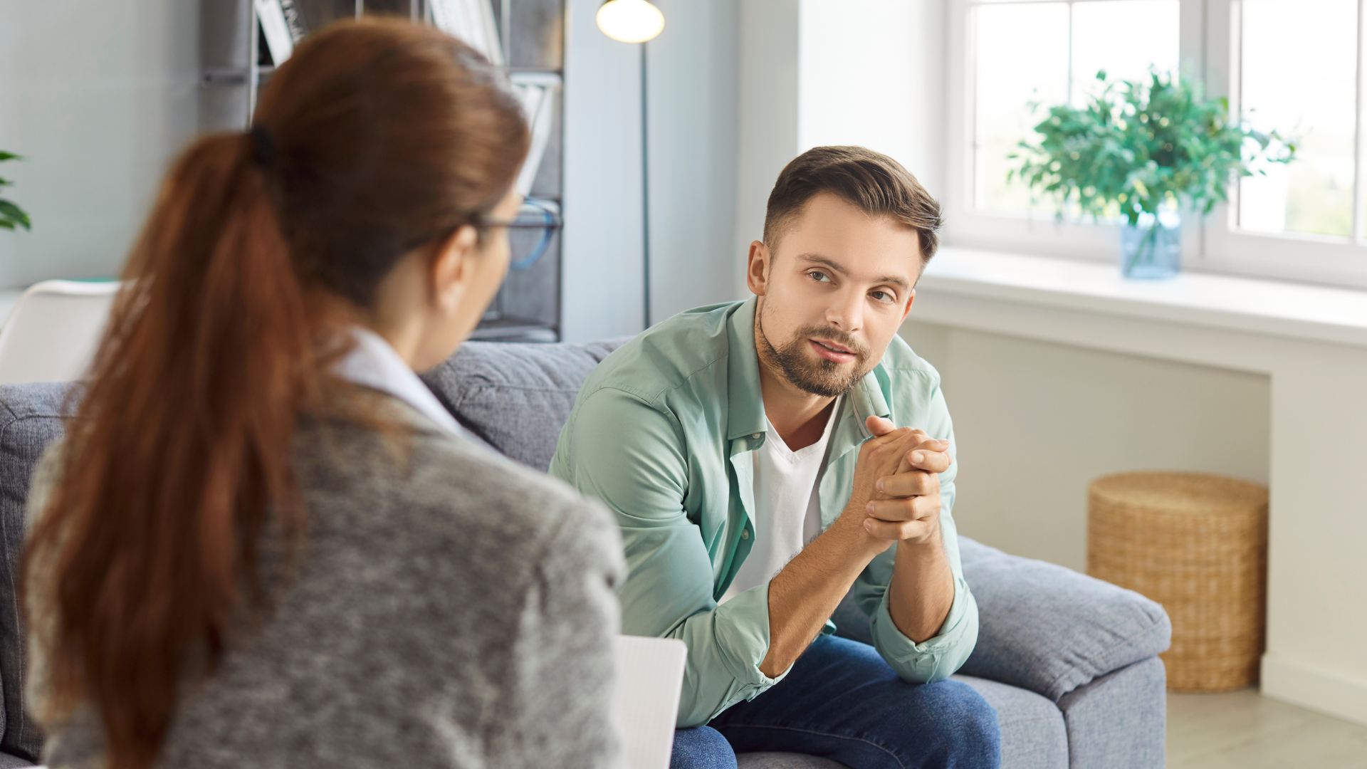 Man listening intently during a conversation with a woman in a bright living room