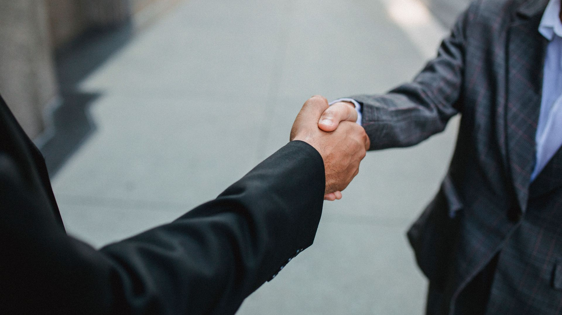 Two people in suits shaking hands in a business setting