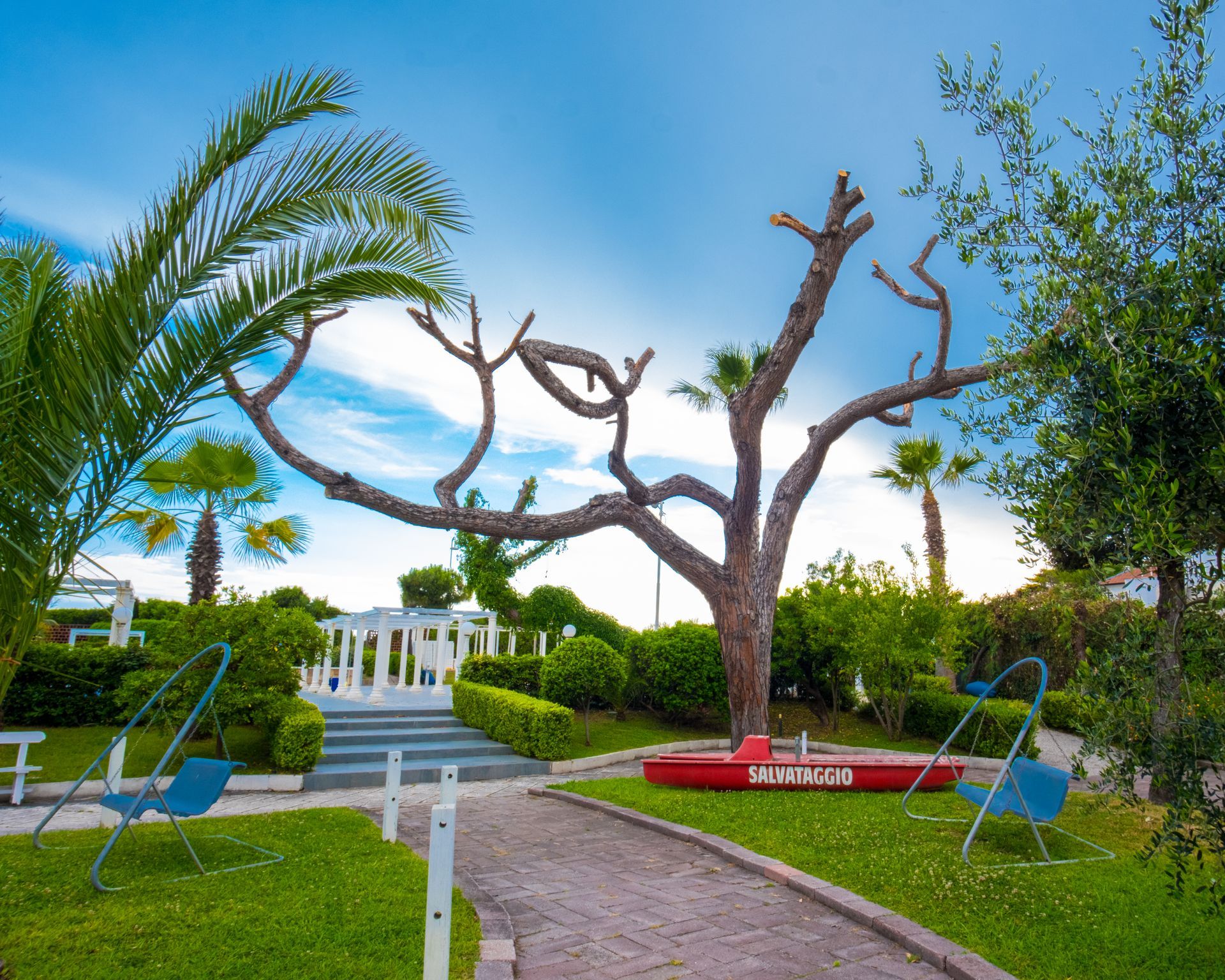 Vista sul resort costiero con vegetazione, orizzonte oceanico e piscina sotto un cielo parzialmente nuvoloso.