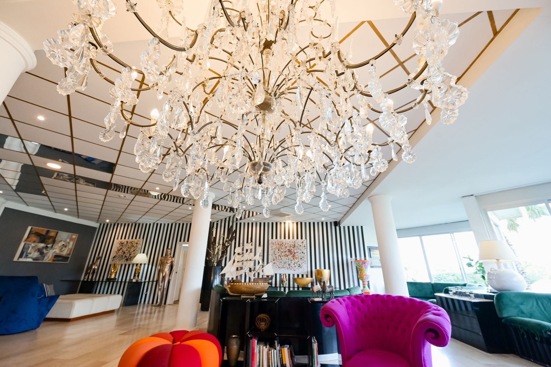Lussuosa hall con soffitto a lampadario, poltrone in velluto colorato e luminosa area salotto moderna.