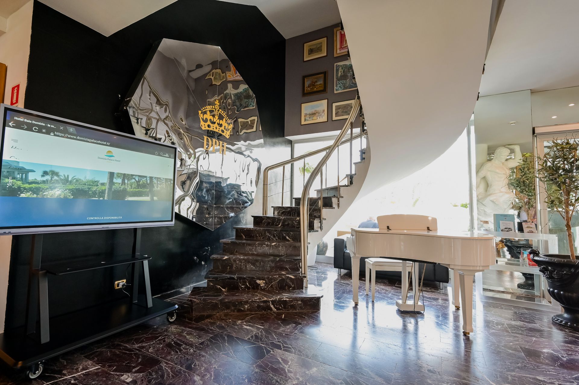 Soggiorno moderno con TV, scala, pianoforte e pavimenti neri lucidi in un interno luminoso