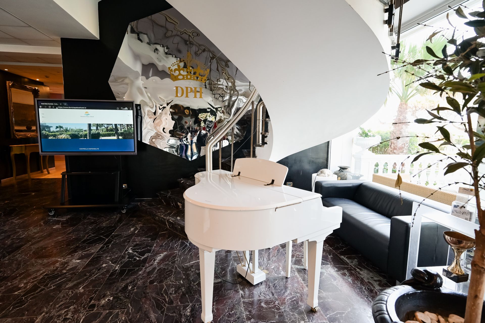 Soggiorno moderno con pianoforte a coda bianco, pavimento in marmo nero, TV e ampio angolo salotto vicino alla finestra.