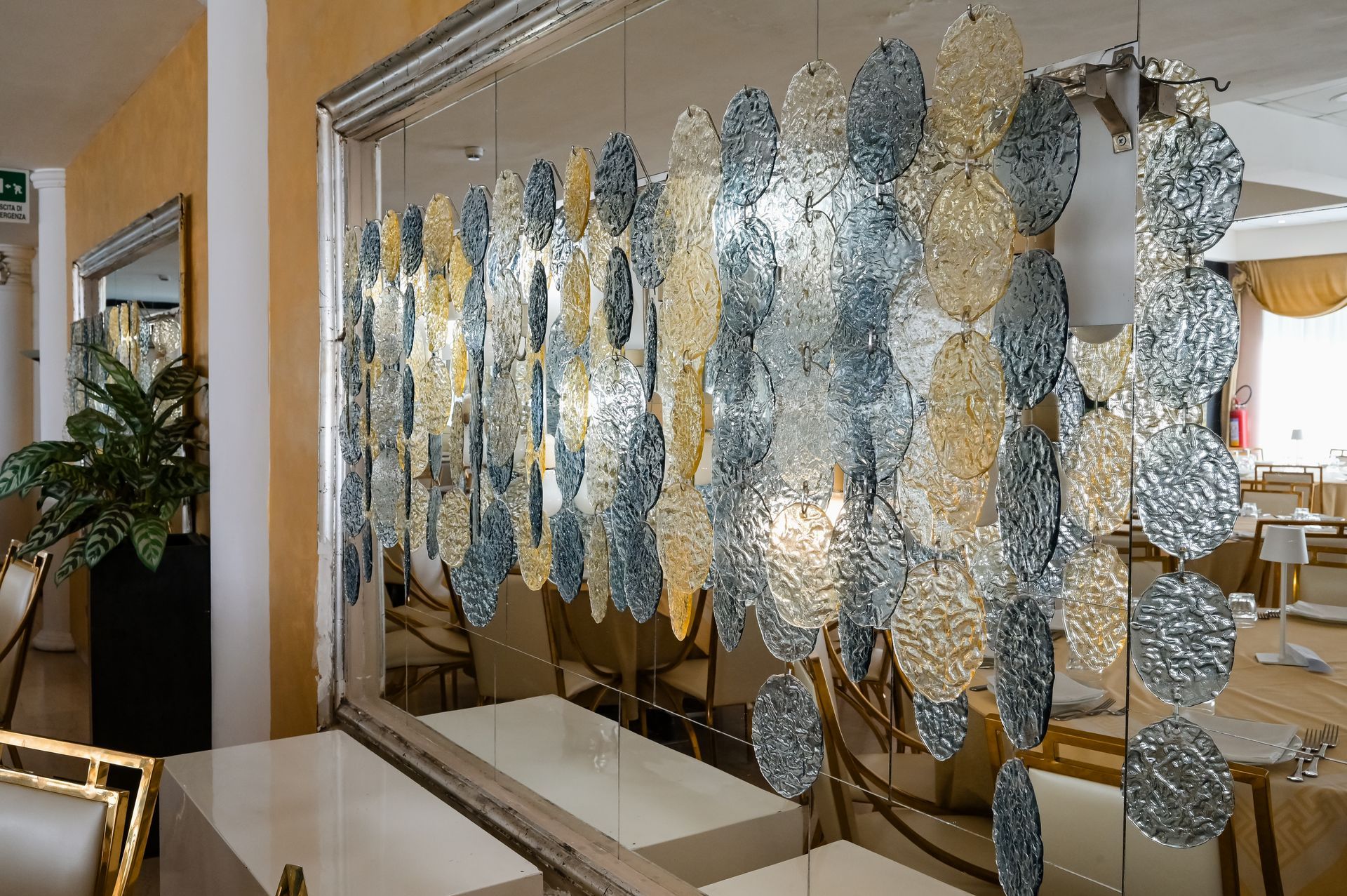 Decorazione murale a forma di foglia in vetro in un luminoso corridoio interno con pannelli a specchio