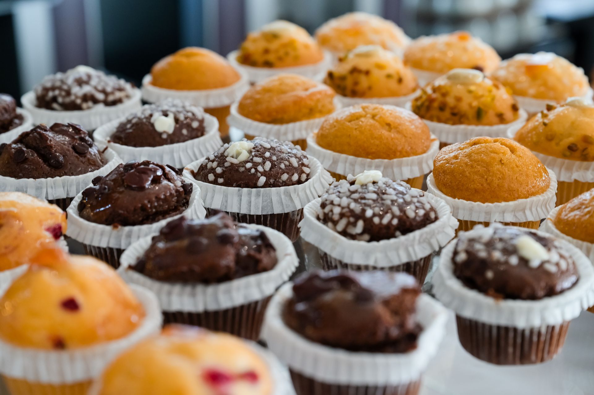 File di cupcake al cioccolato e dorati in pirottini bianchi su un vassoio