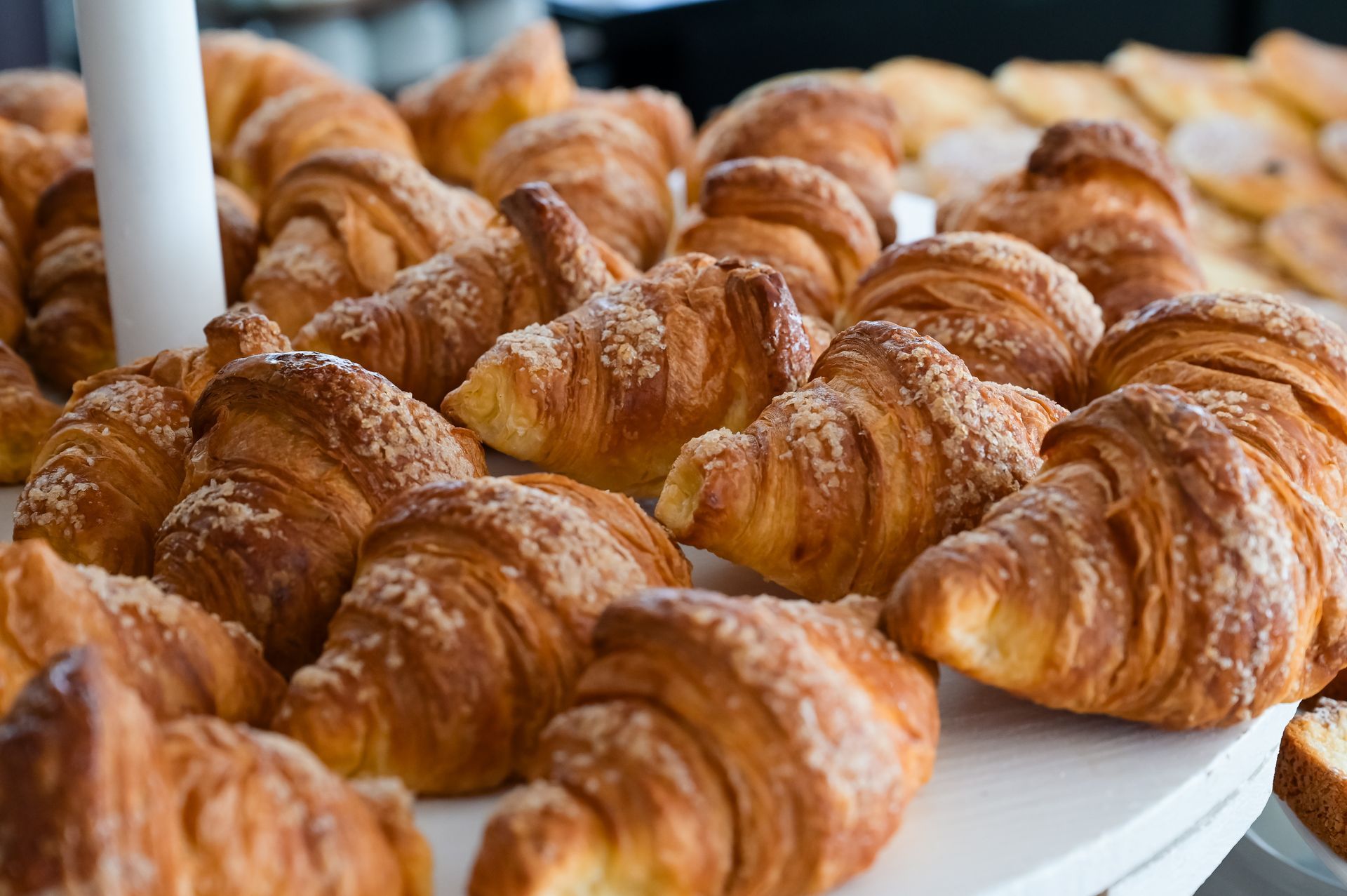 Vassoio di croissant dorati cosparsi di zucchero a velo in vetrina in una pasticceria.