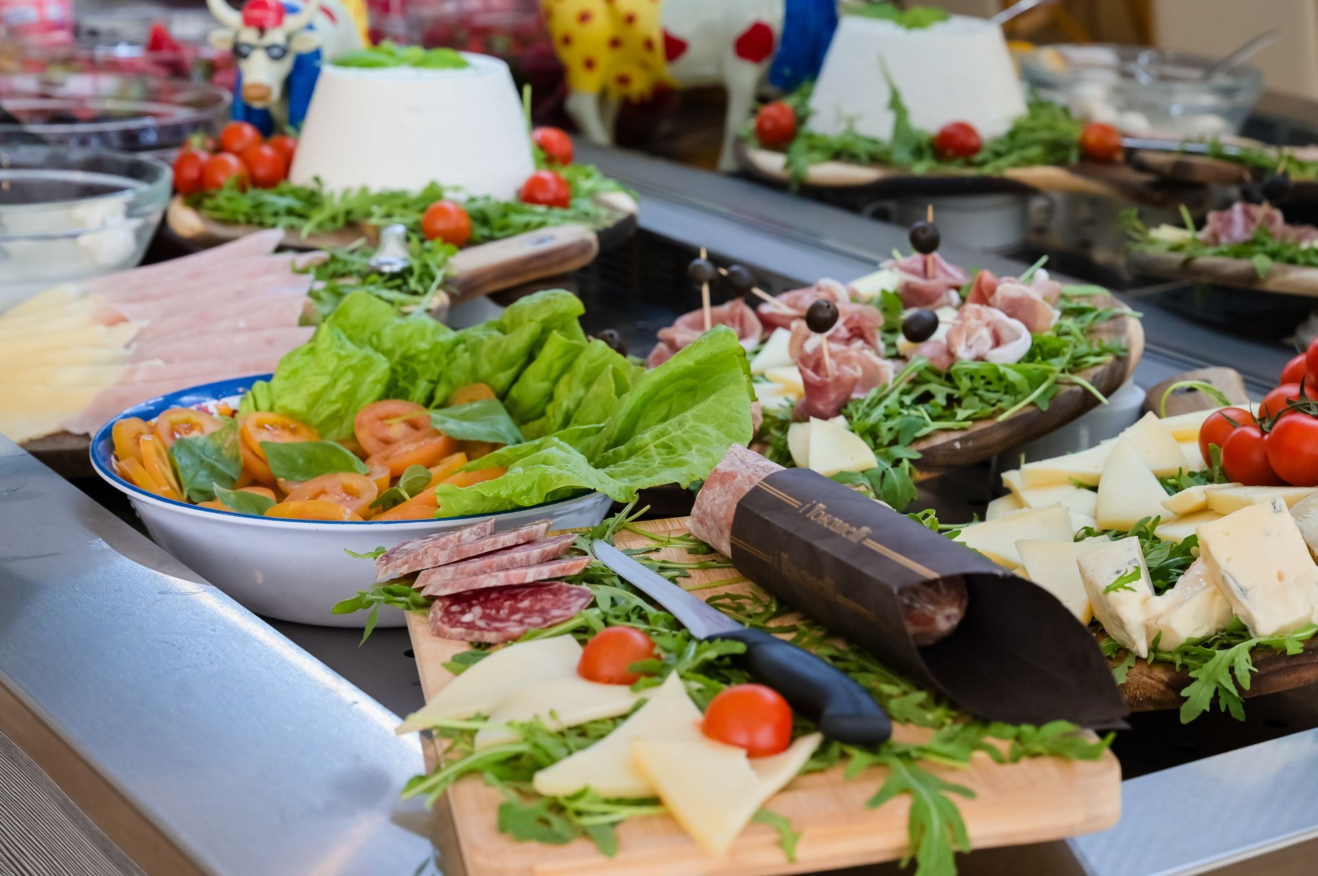 Antipasti assortiti su un vassoio da buffet con lattuga, affettati, formaggio, olive e pomodorini.