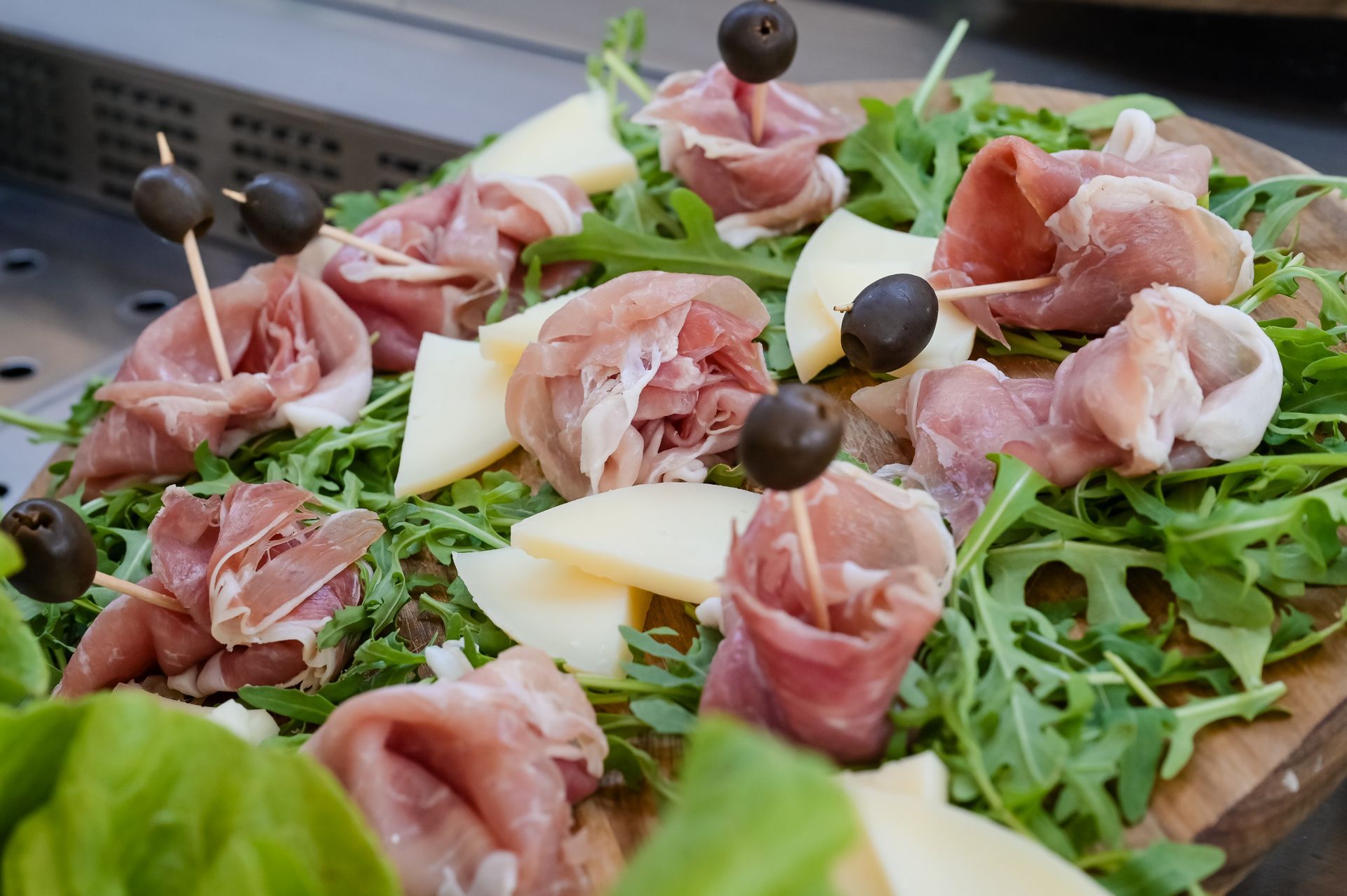 Antipasto di prosciutto e formaggio su rucola con olive su un piatto scuro
