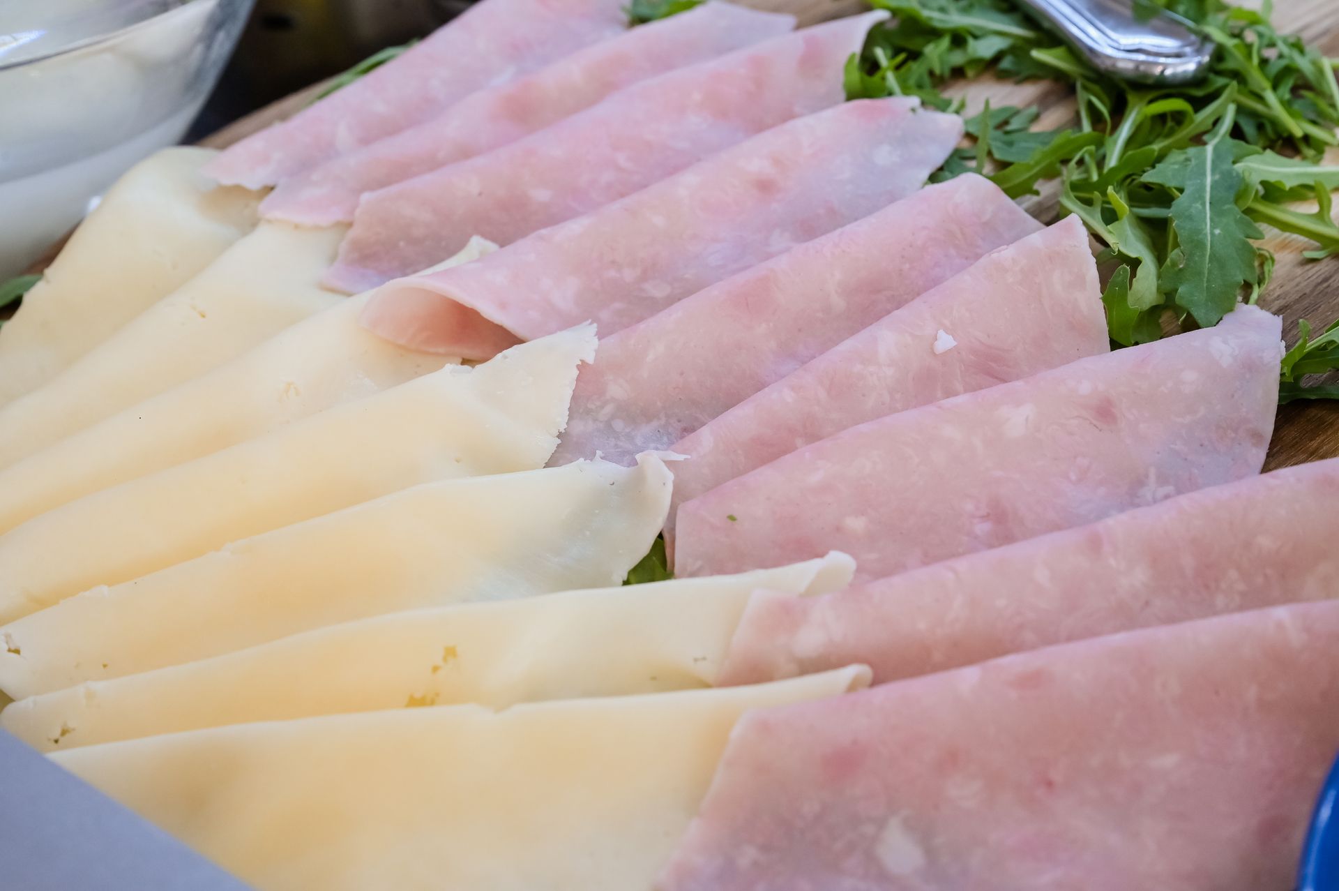 Sashimi assortito rosa e giallo pallido tagliato a fettine sottili, disposto a ventaglio su un piatto con verdure