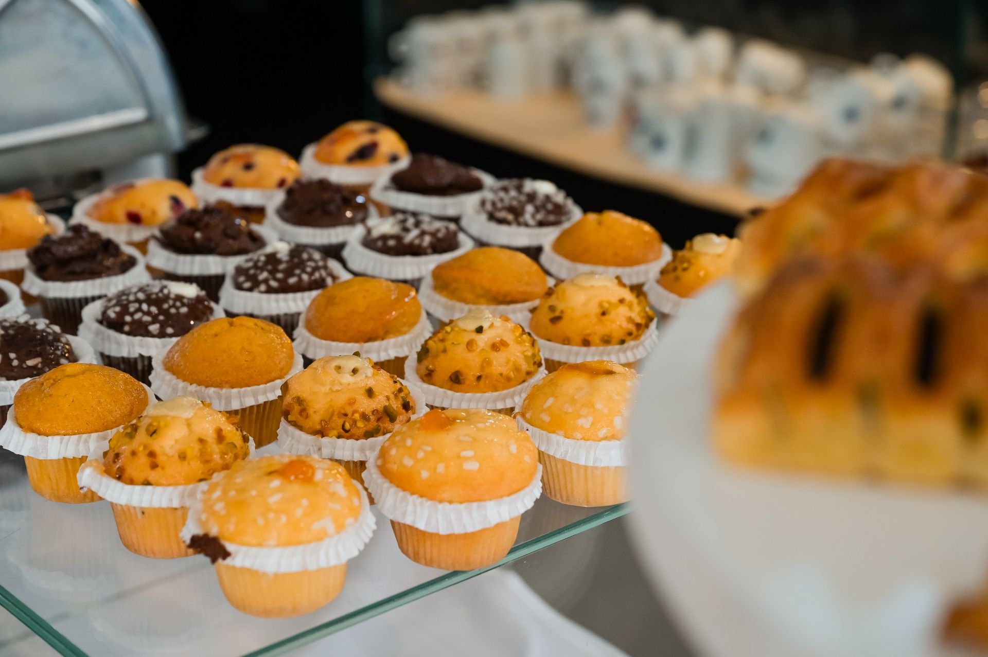 File di mini cupcake all'arancia e al cioccolato su un vassoio di vetro su un tavolo dei dolci.