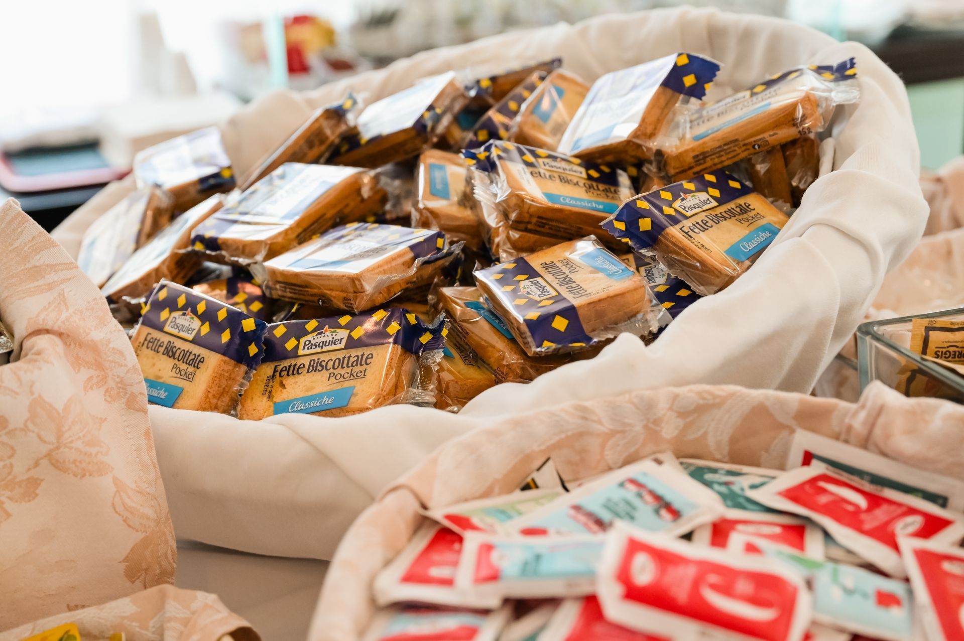 Ciotola di snack confezionati singolarmente con etichette blu e oro accanto a pacchetti rossi e bianchi