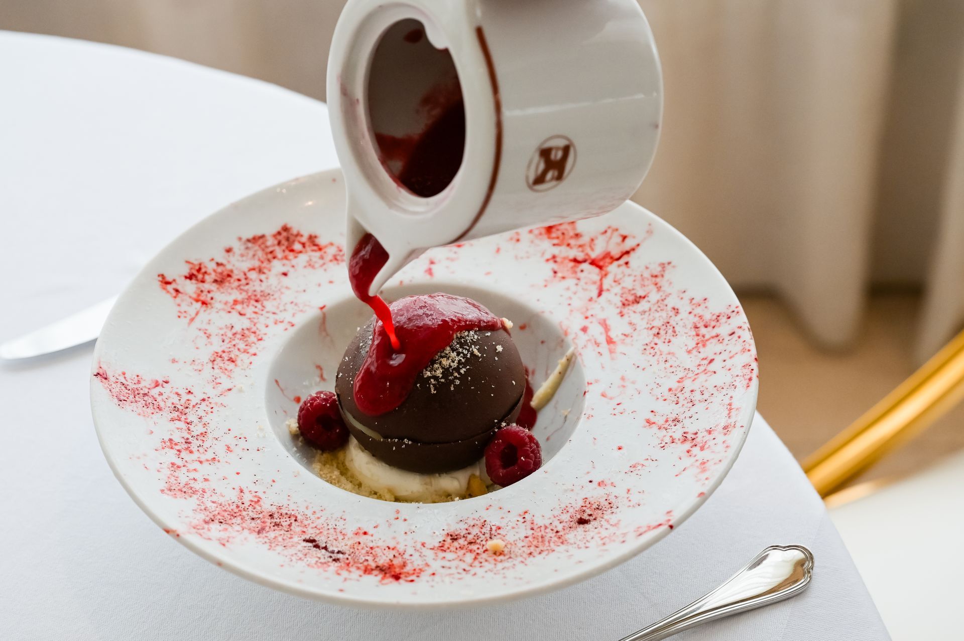 Dessert al cioccolato con salsa rossa versata su un piatto bianco e guarnito con frutti di bosco.