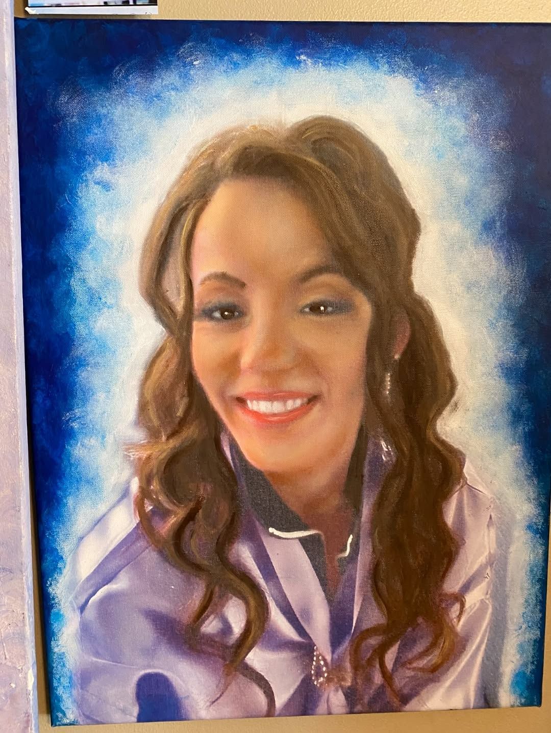 Smiling woman in a purple blouse against a blue and white painted background