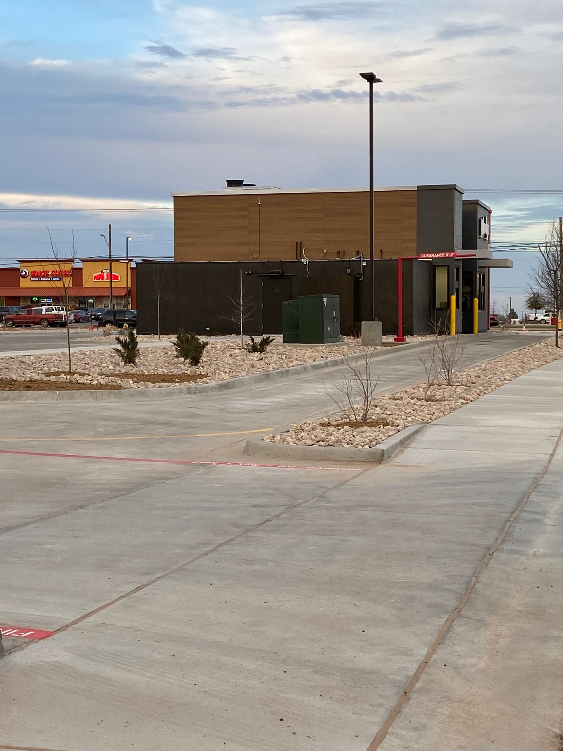 Modern building beside a snowy parking lot, with a red truck and cloudy sky in the background