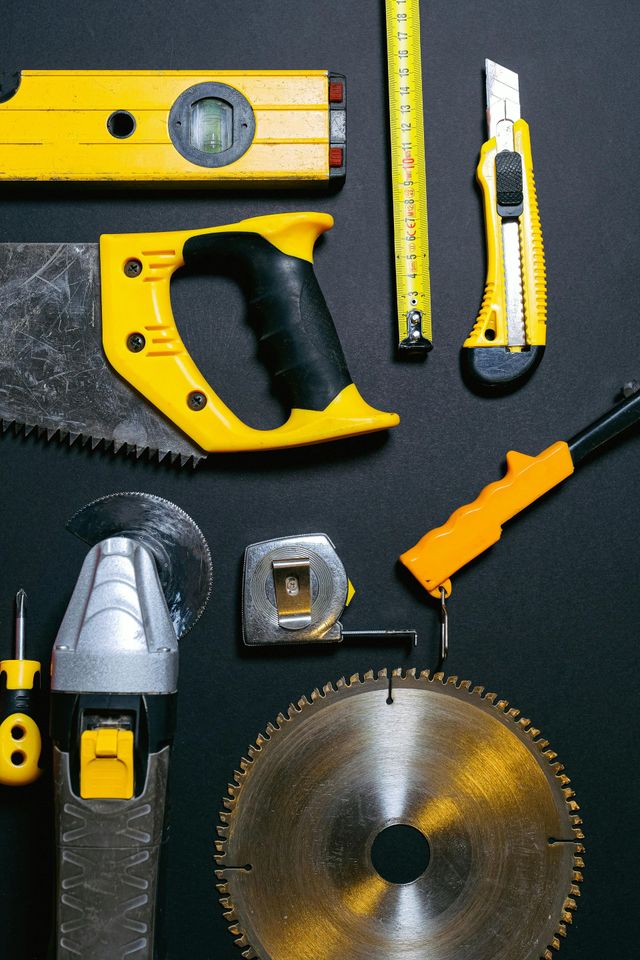 construction tools: level, saw, tape measure, utility knife, hammer, angle grinder, screwdriver, and circular saw blade.