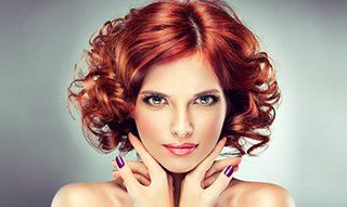 A lady with a glossy red curly hairstyle